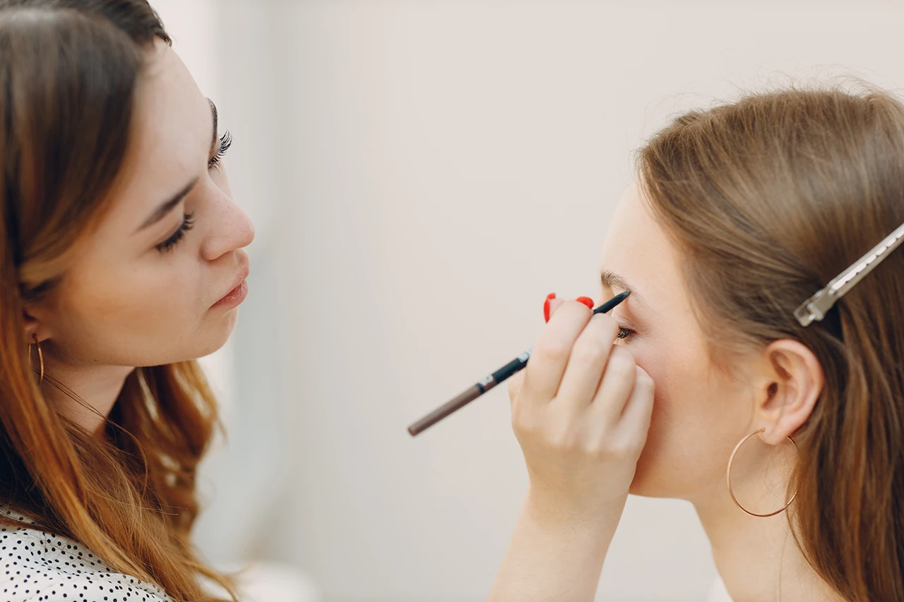 Makeup artist applying brow pencil during bridal makeup home service.