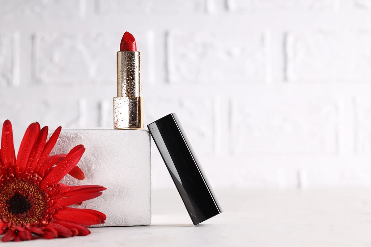 The best wedding lipstick in bright red next to a red flower.