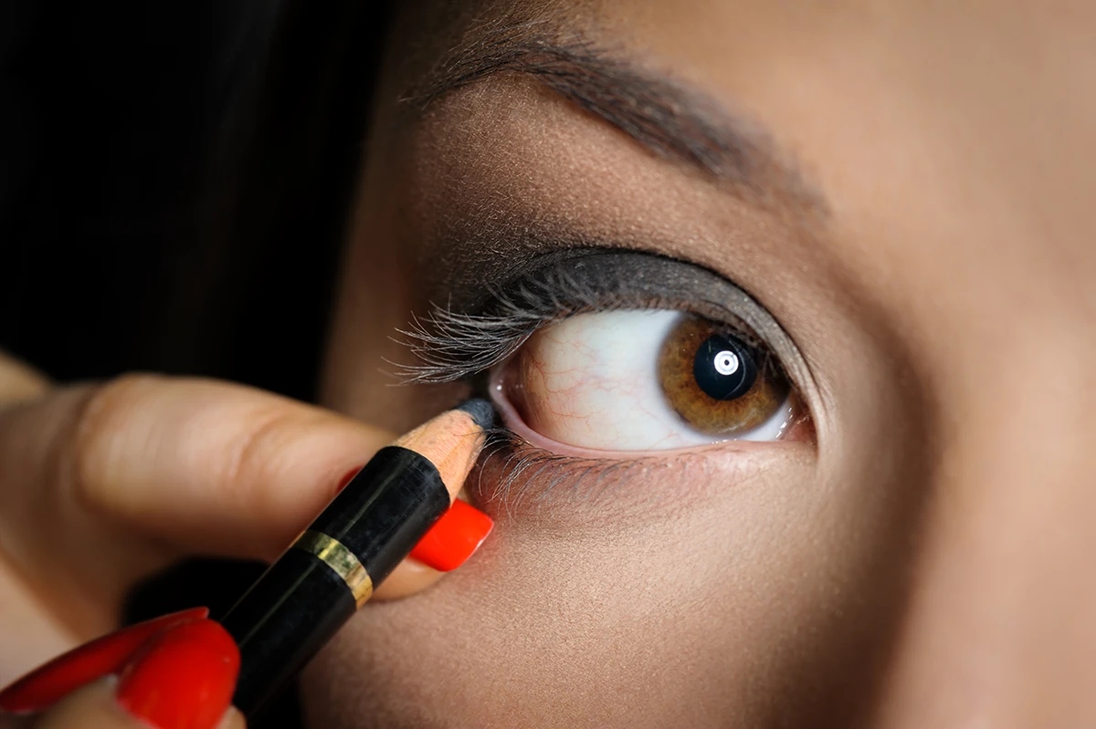 Woman applying eyeliner to her hooded eye.