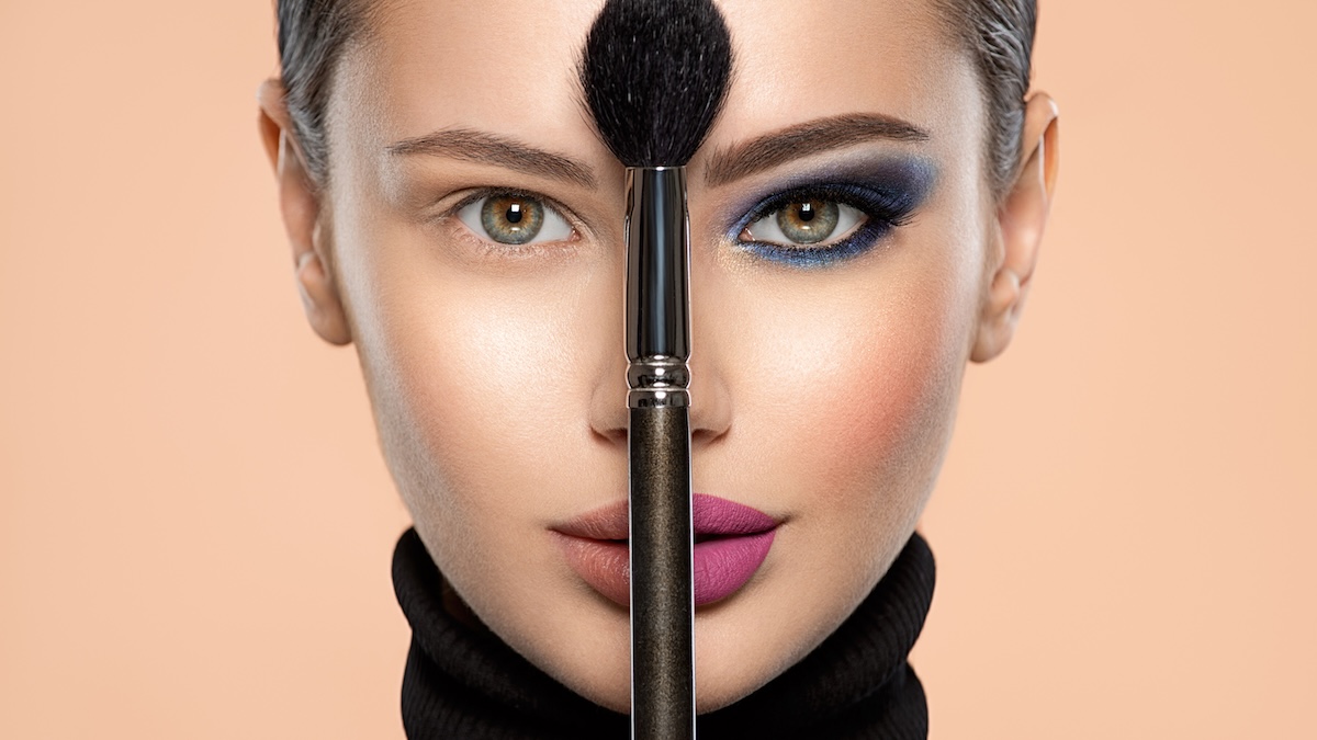 A woman's face split by a brush over her nose, with one side showing her bare eye and the other side showing the result of our makeup tips for hooded eyes.