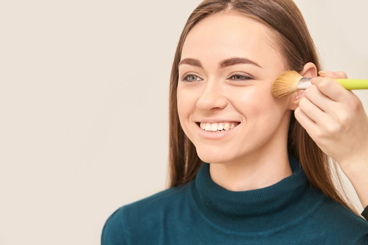 Woman smiling while getting shown how to contour her oval face.