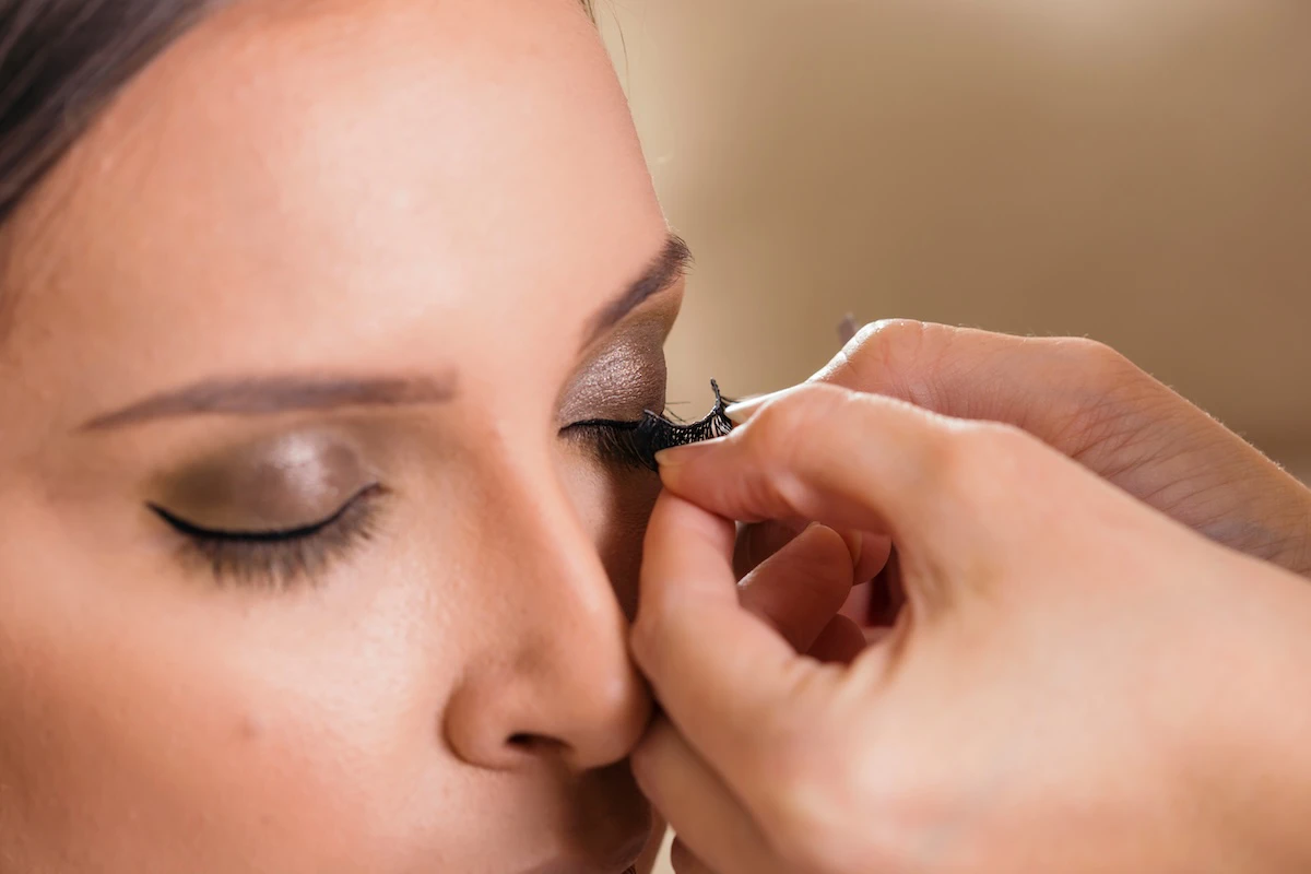 Woman getting eyelash strips applied the right way.