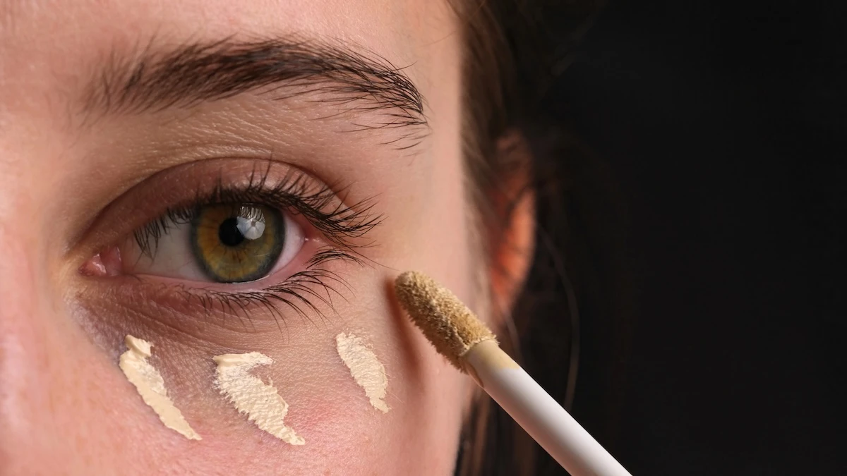 Girl showing how to apply concealer under the eye correctly.