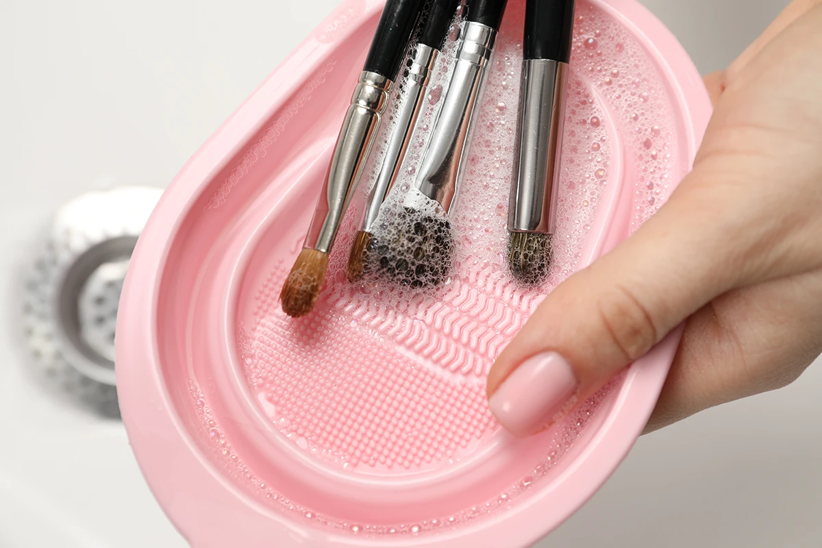 Makeup brushes and sponges being sanitized with soap and water.