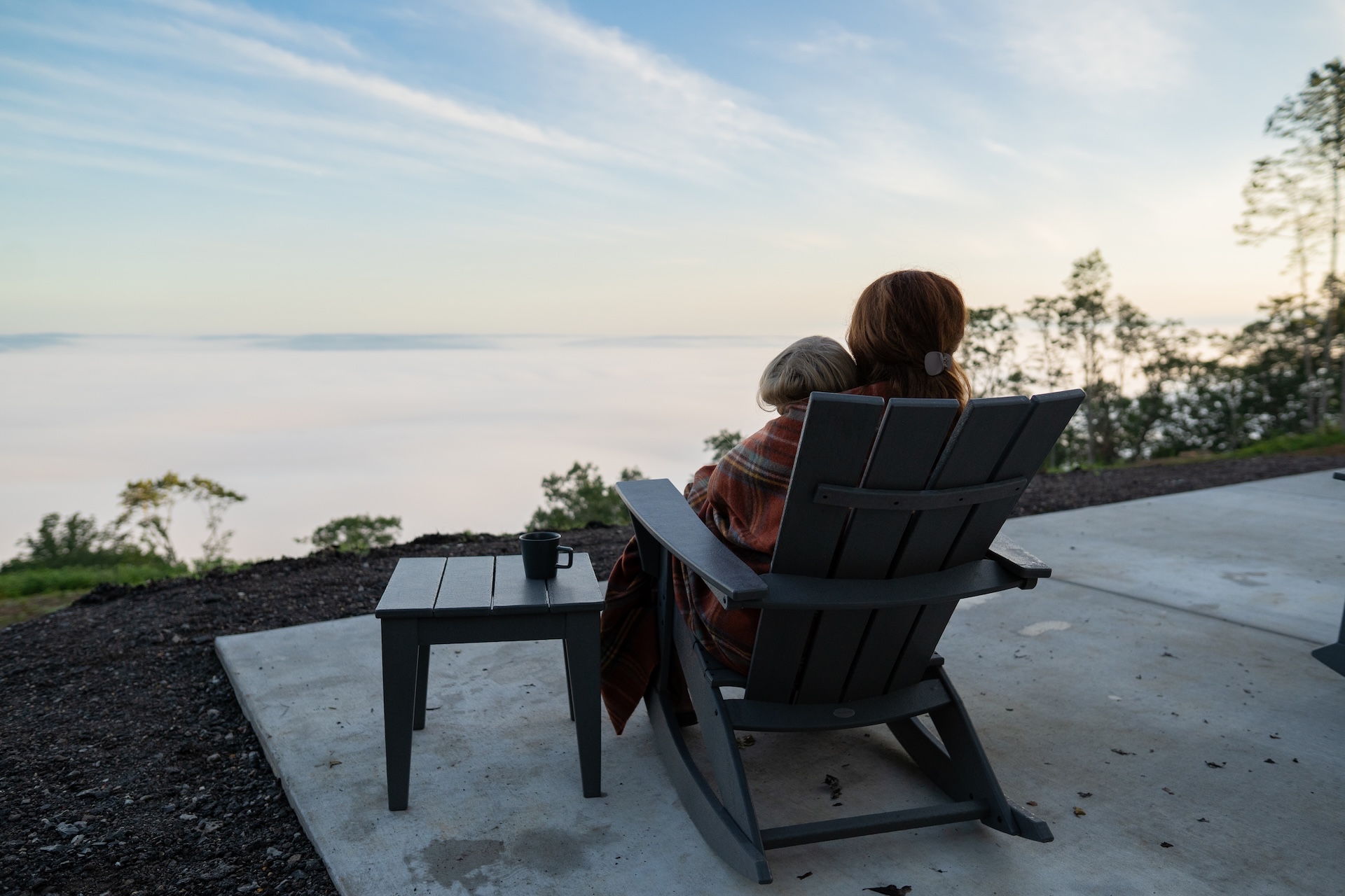 A mother and daughter sit on the patio of their Wind River prefab cabin.