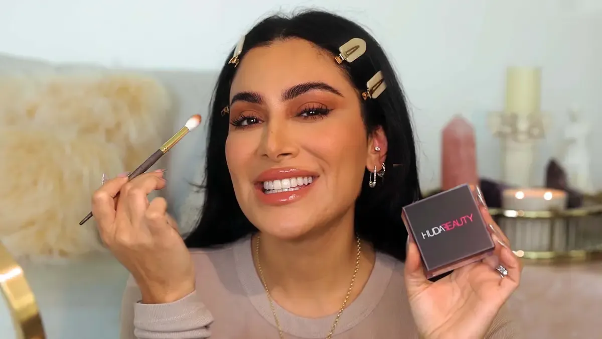 Huda Kattan showcasing HudaBeauty's beauty products.