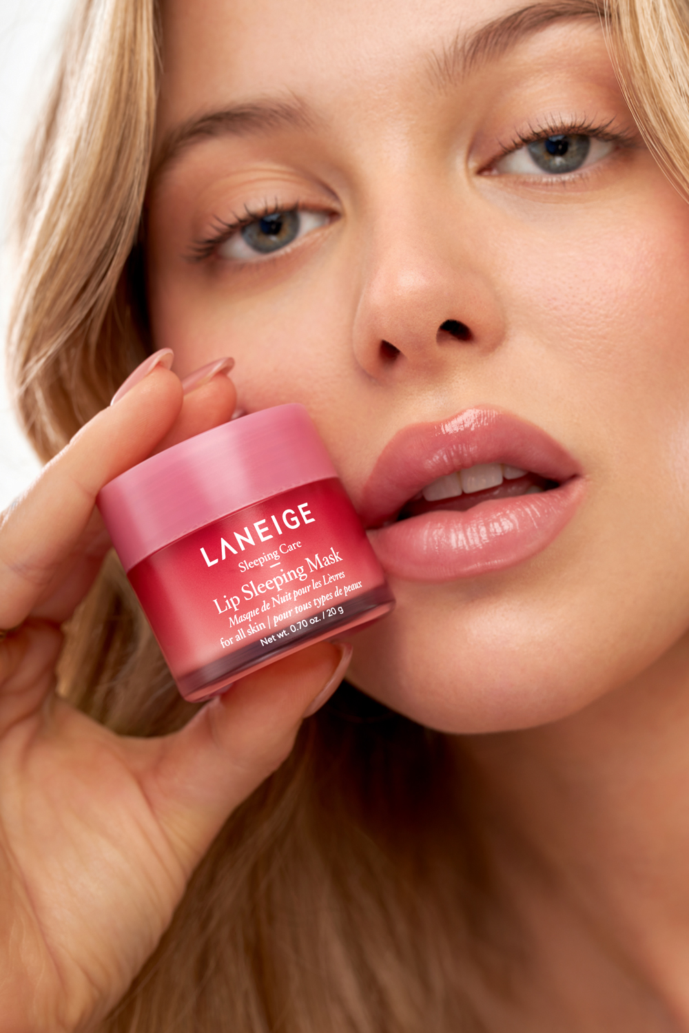 A woman holding a tube of LANEIGE lip sleeping mask.