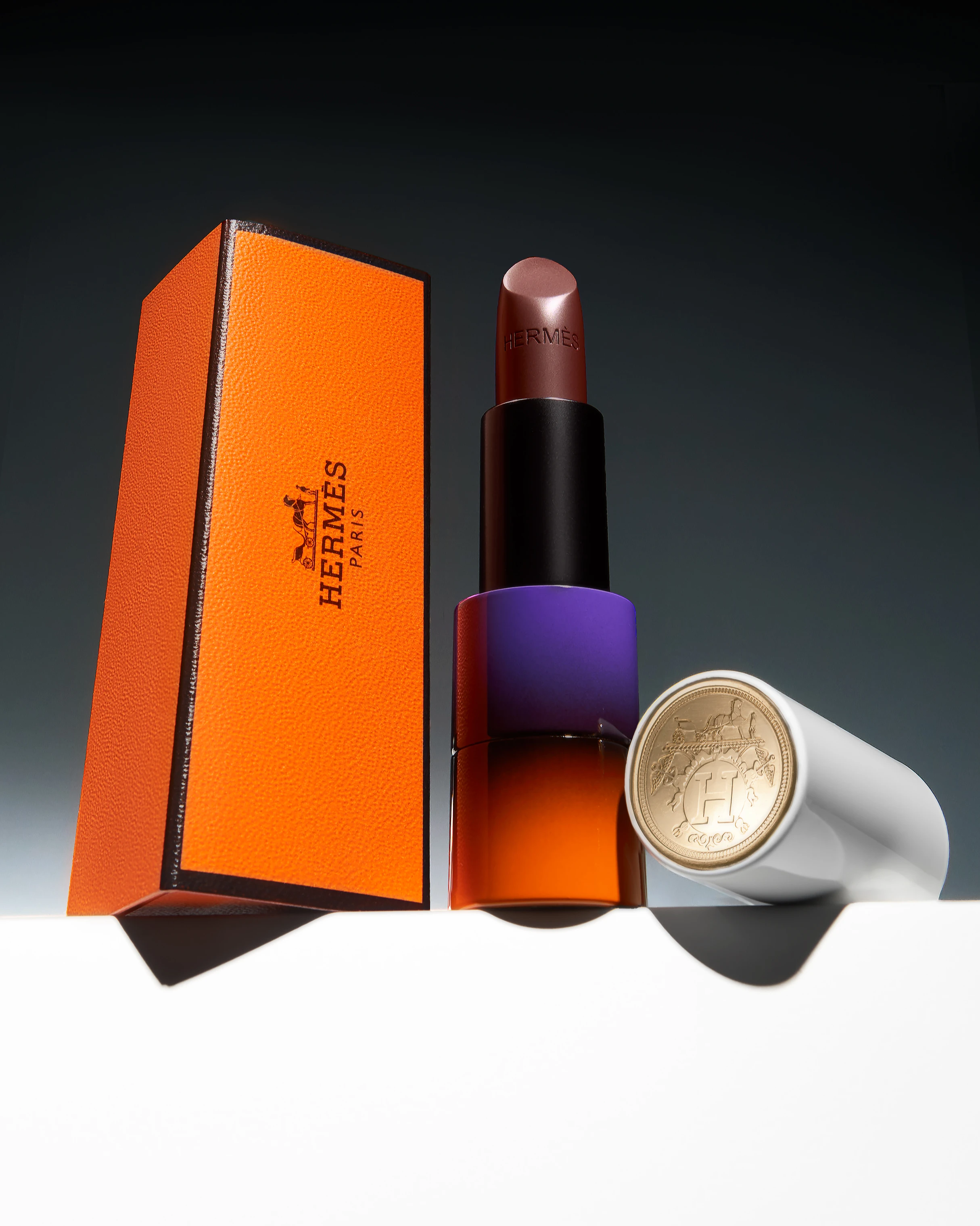 A Hermes lipstick box with a lipstick and a coin.