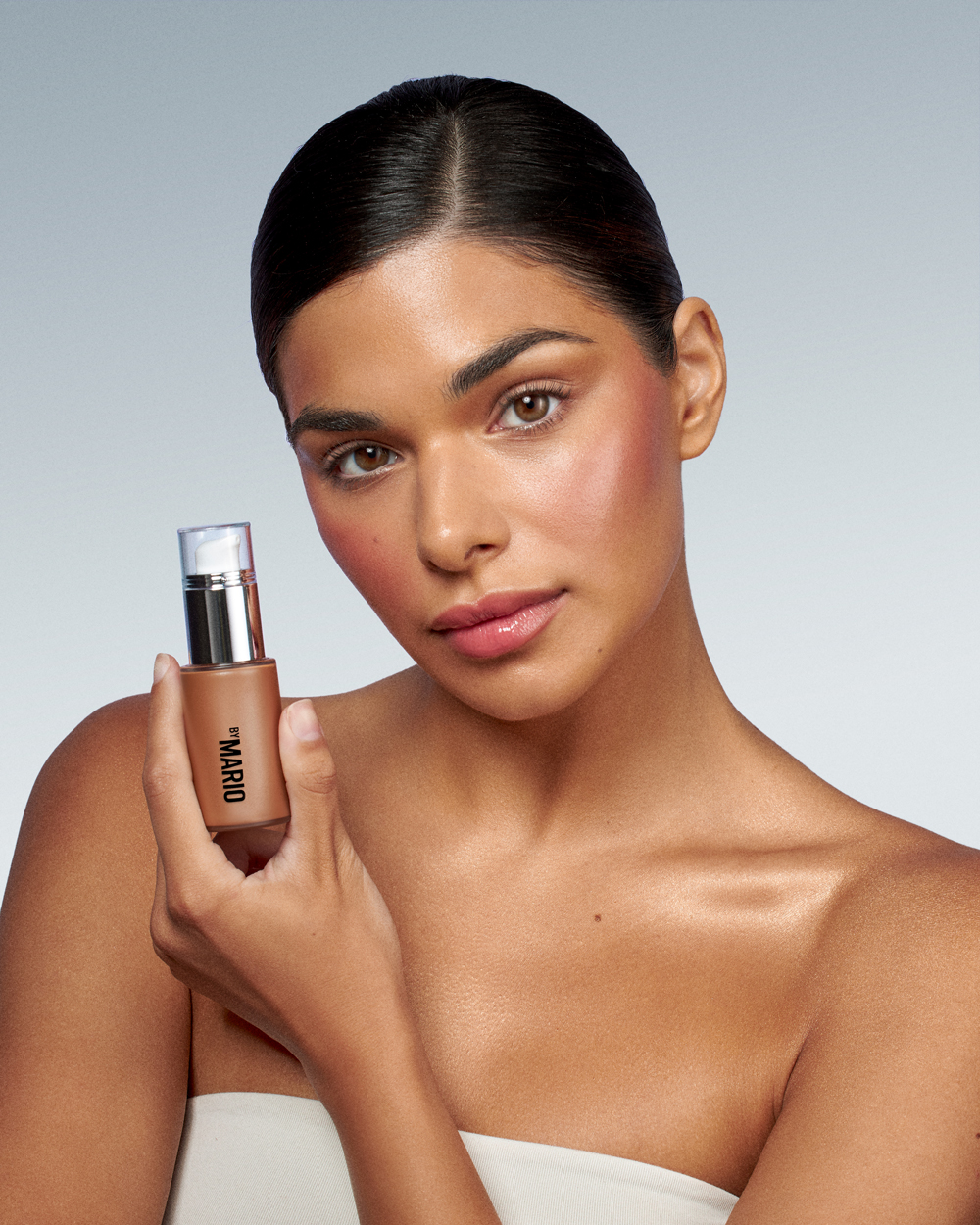 A woman holding a bottle of makeup.