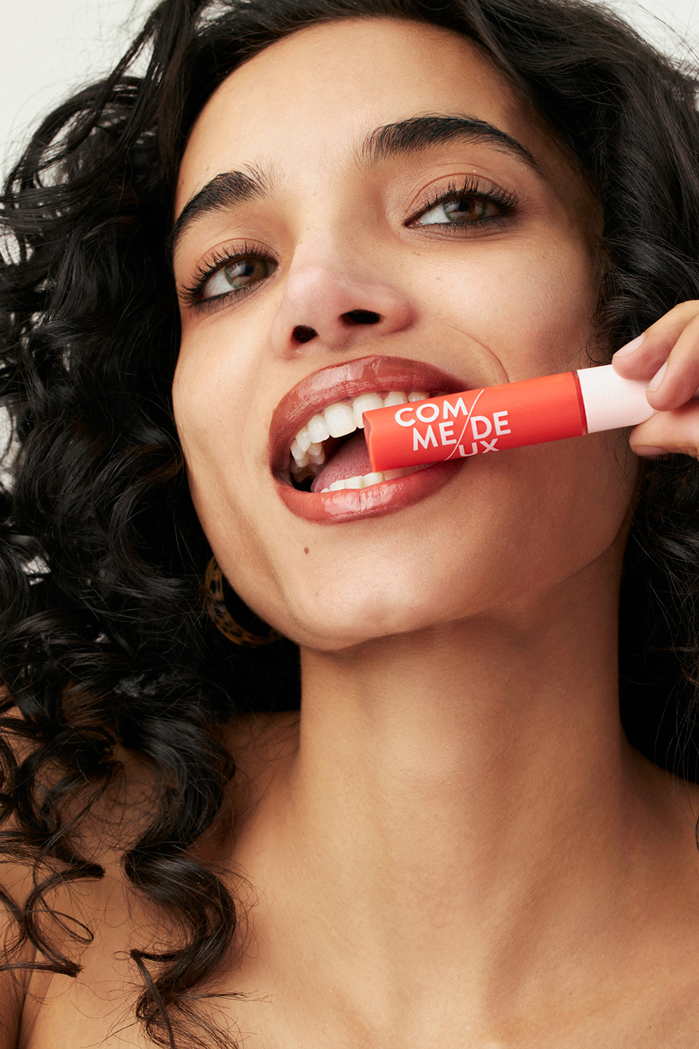 A woman with dark hair and a red lipstick on her lips.