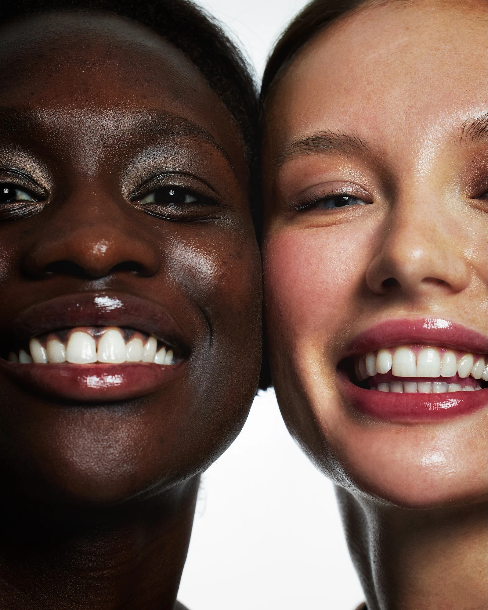 Two women with dark skin and white teeth smiling for the camera.