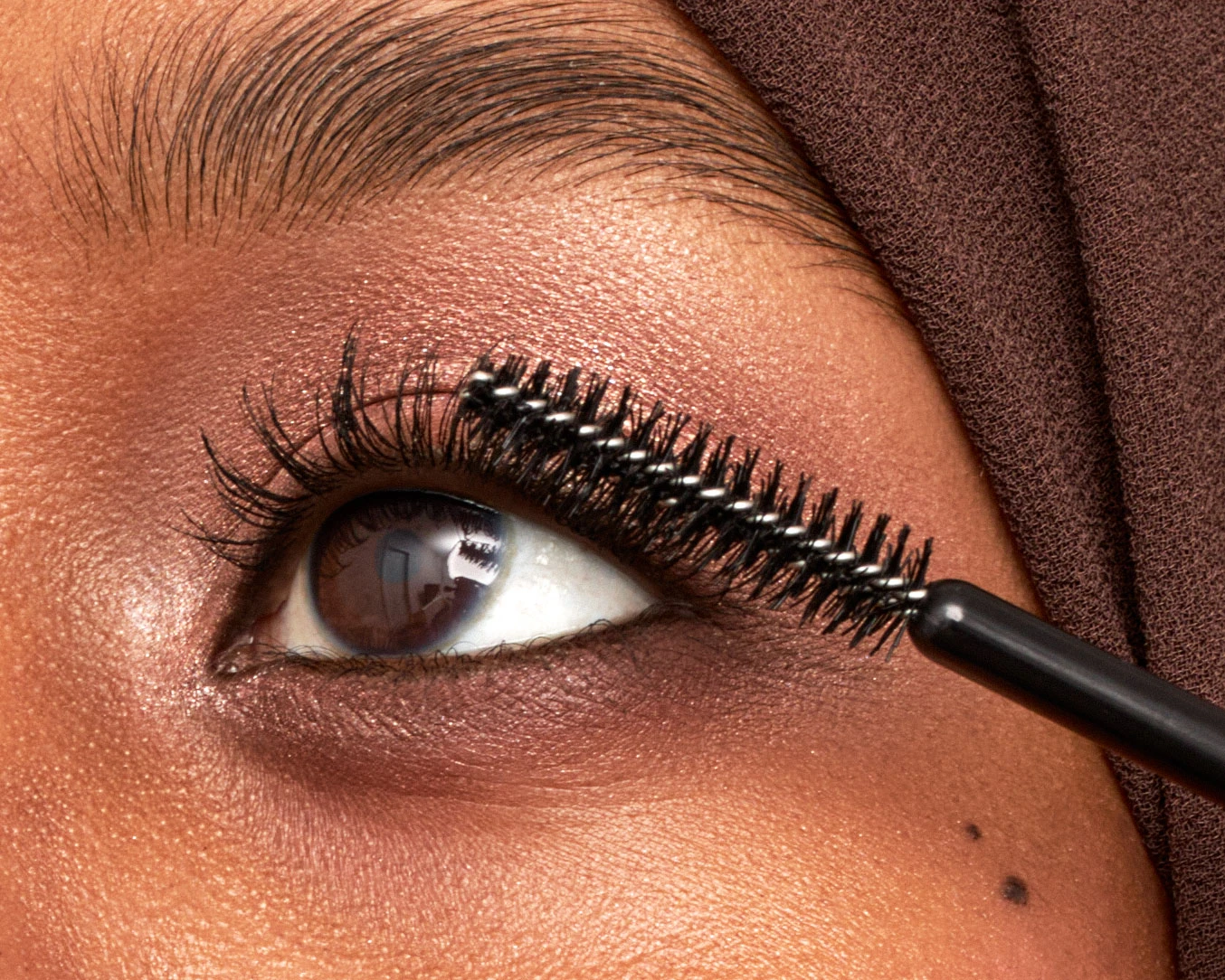 A woman with a brown head scarf and eyelashes.