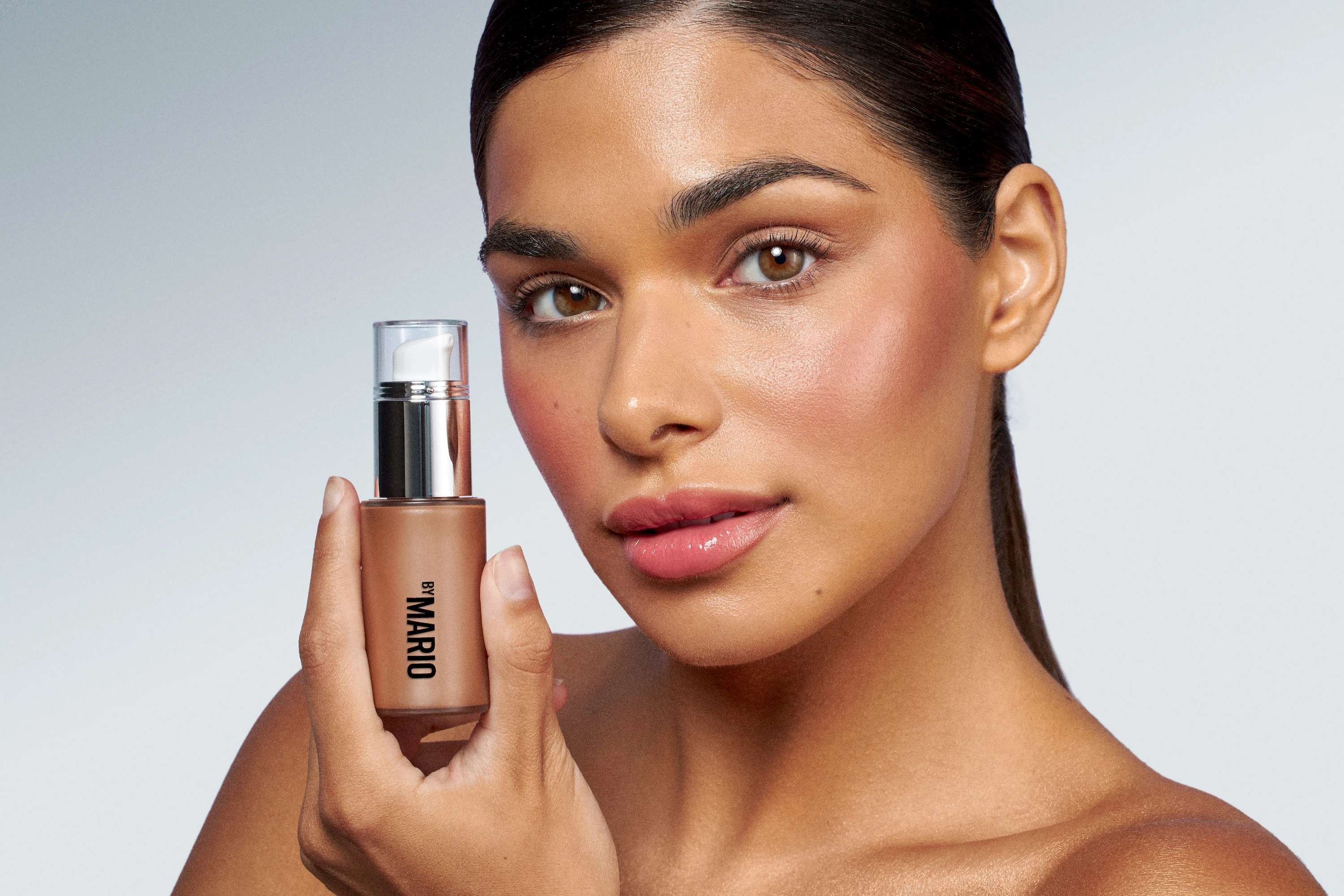 A woman holding a bottle of makeup.