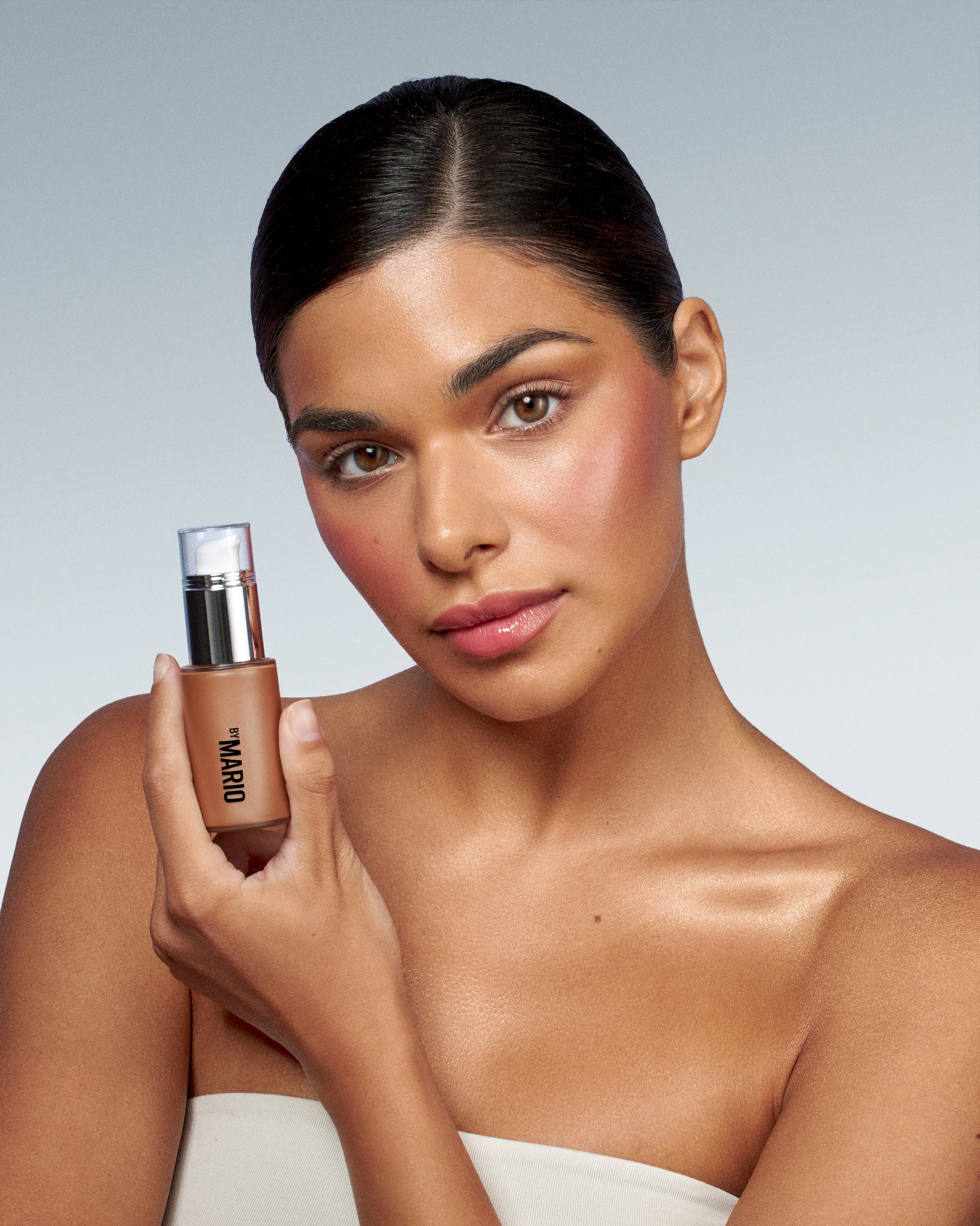 A woman holding a bottle of makeup.