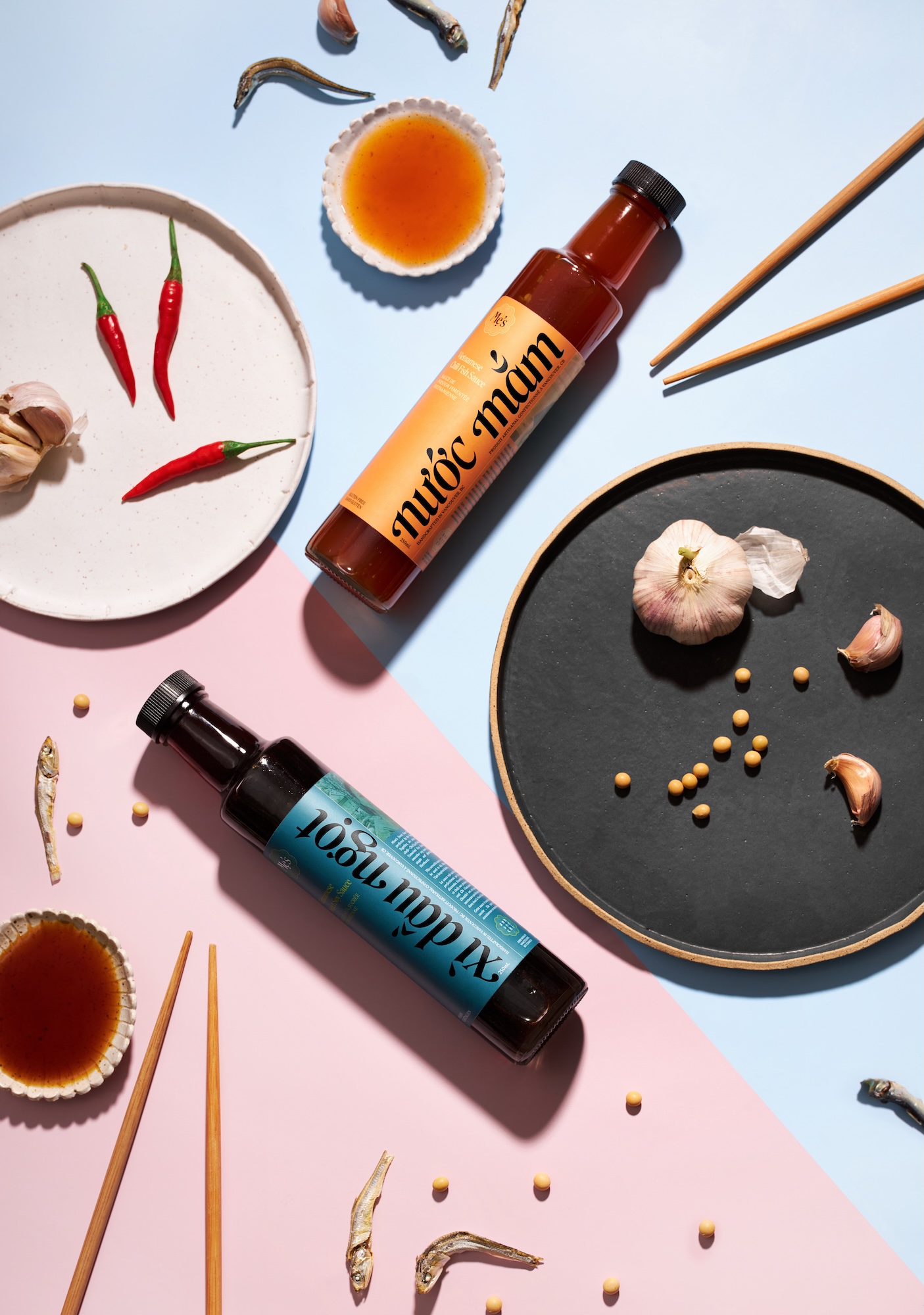 A bottle of sauce and a bottle of seasoning sit on a pink and blue table.