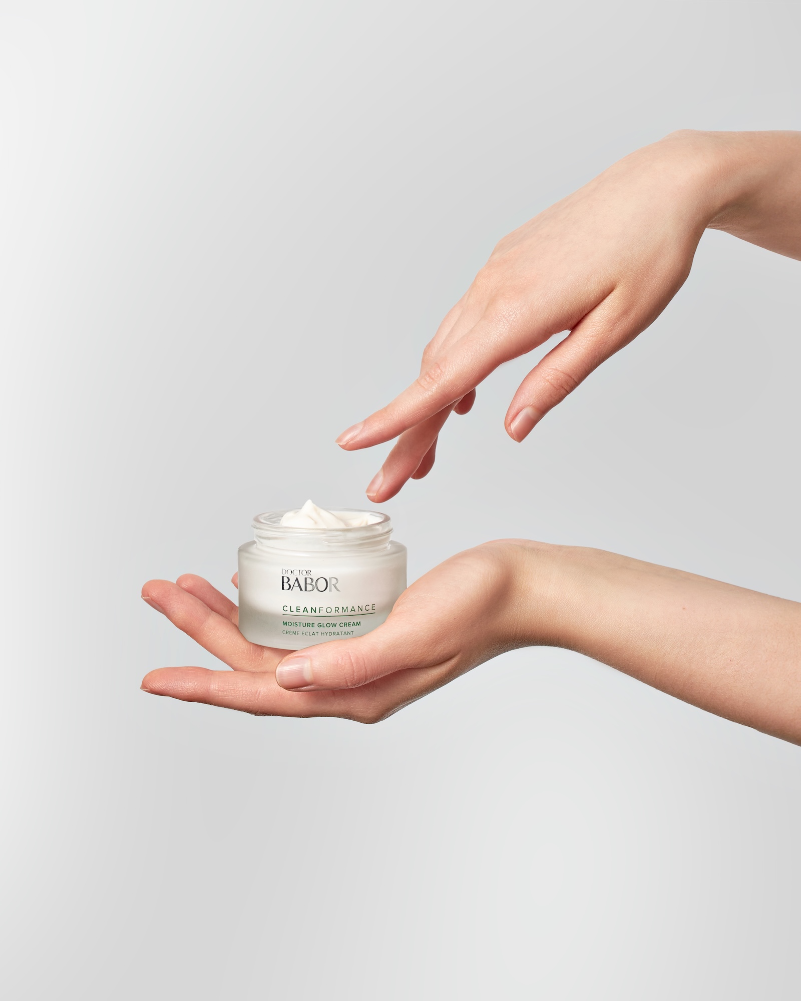 A hand holding a jar of BABOR cream.
