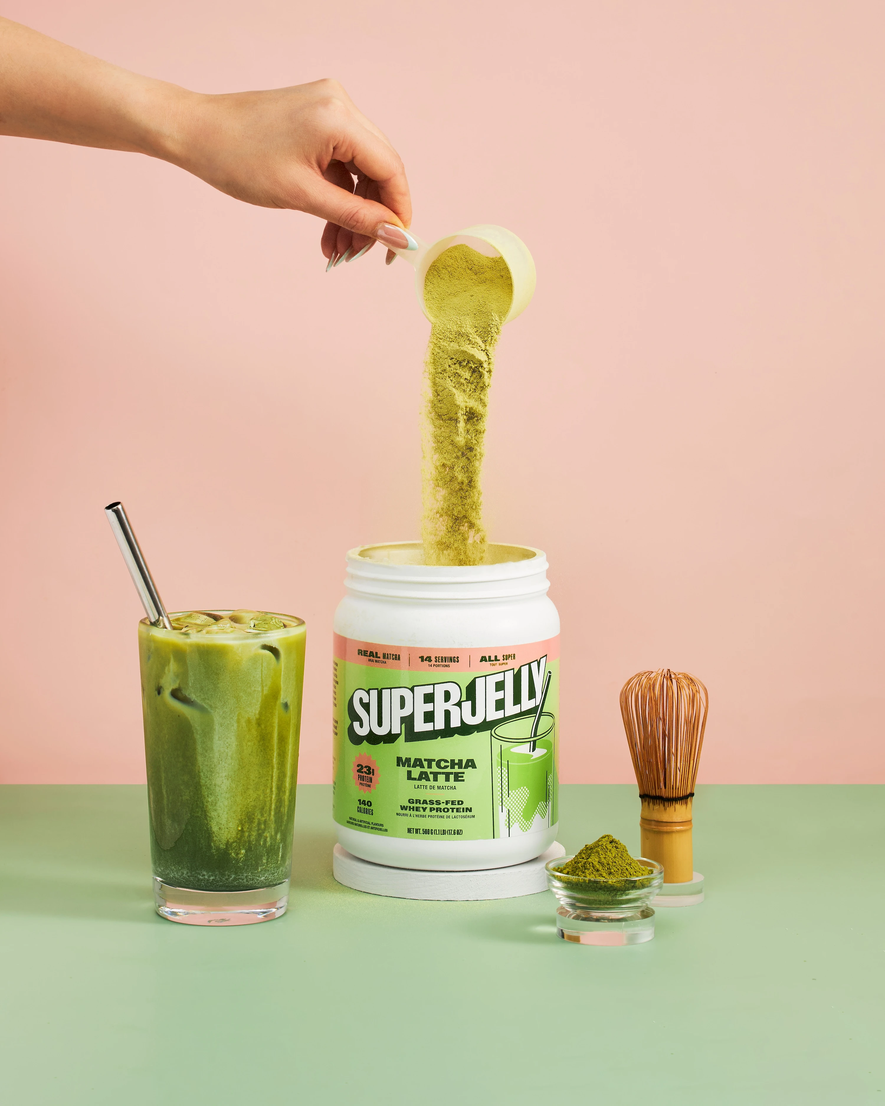 A glass of green smoothie with a spoon in it.