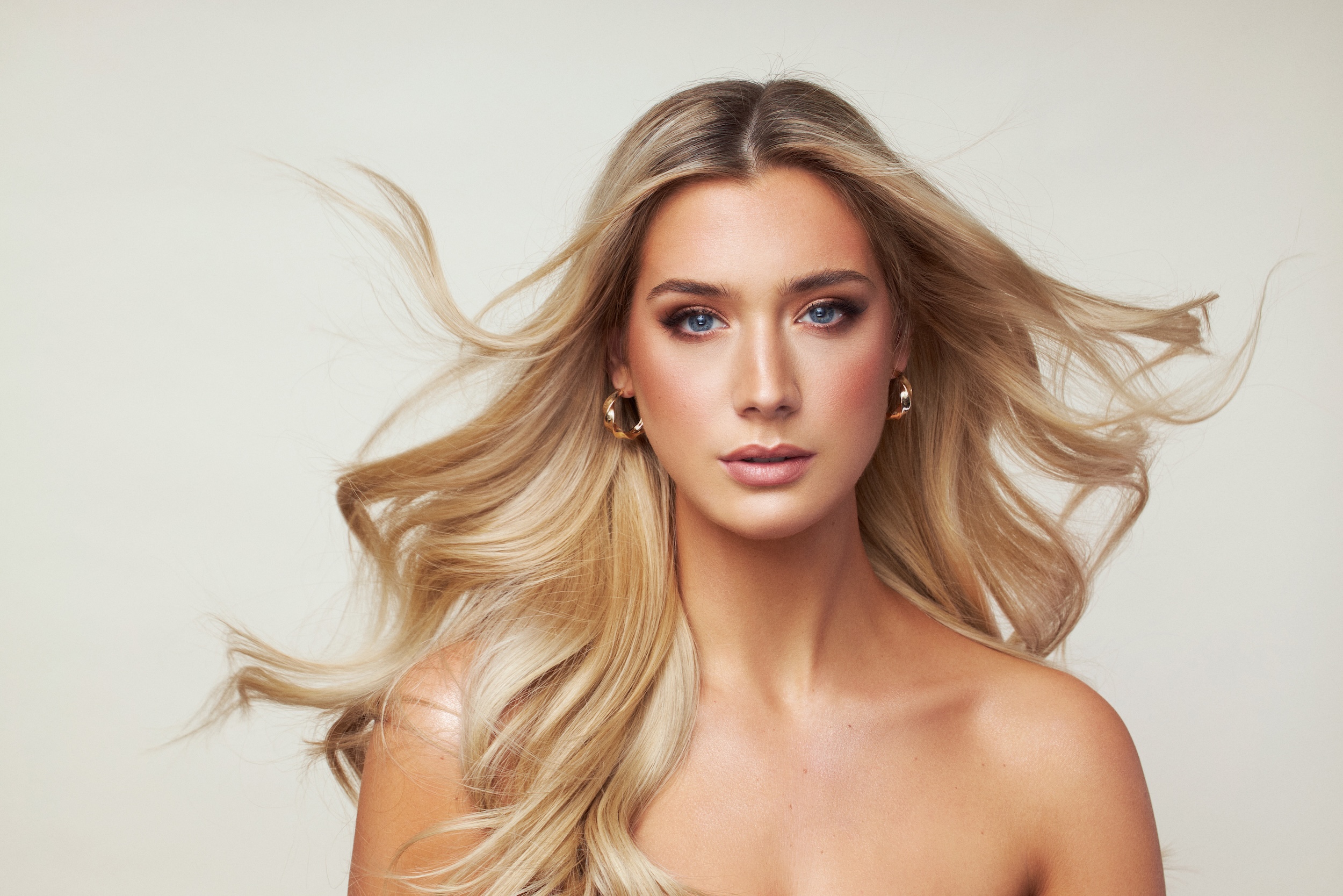 A blonde woman with a ponytail and earrings.