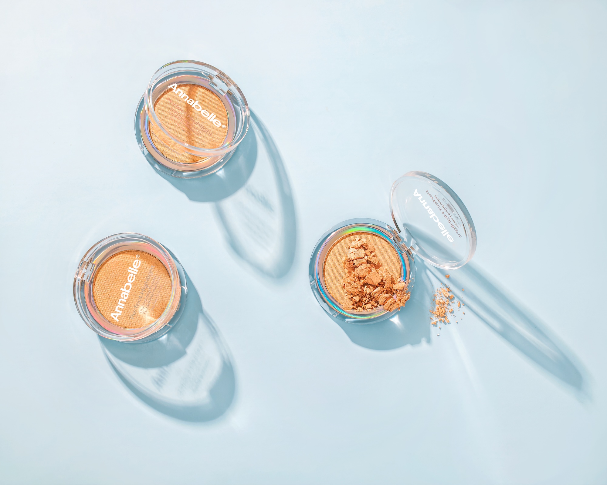 Three containers of Anabelle sandalwood oil makeup are on a blue table.