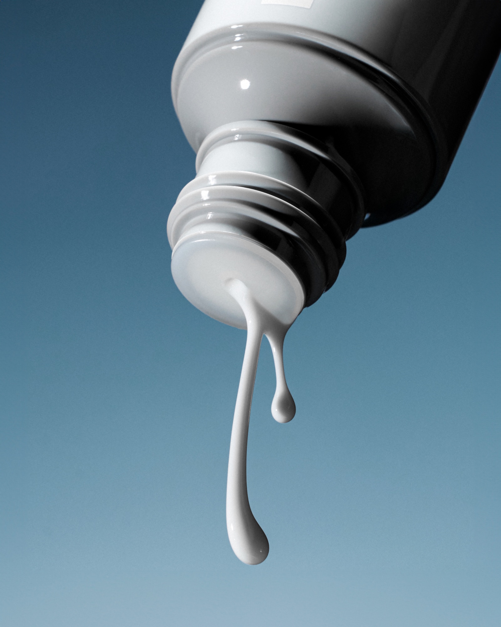 A bottle of Rhode lotion with a droplet of lotion coming out.