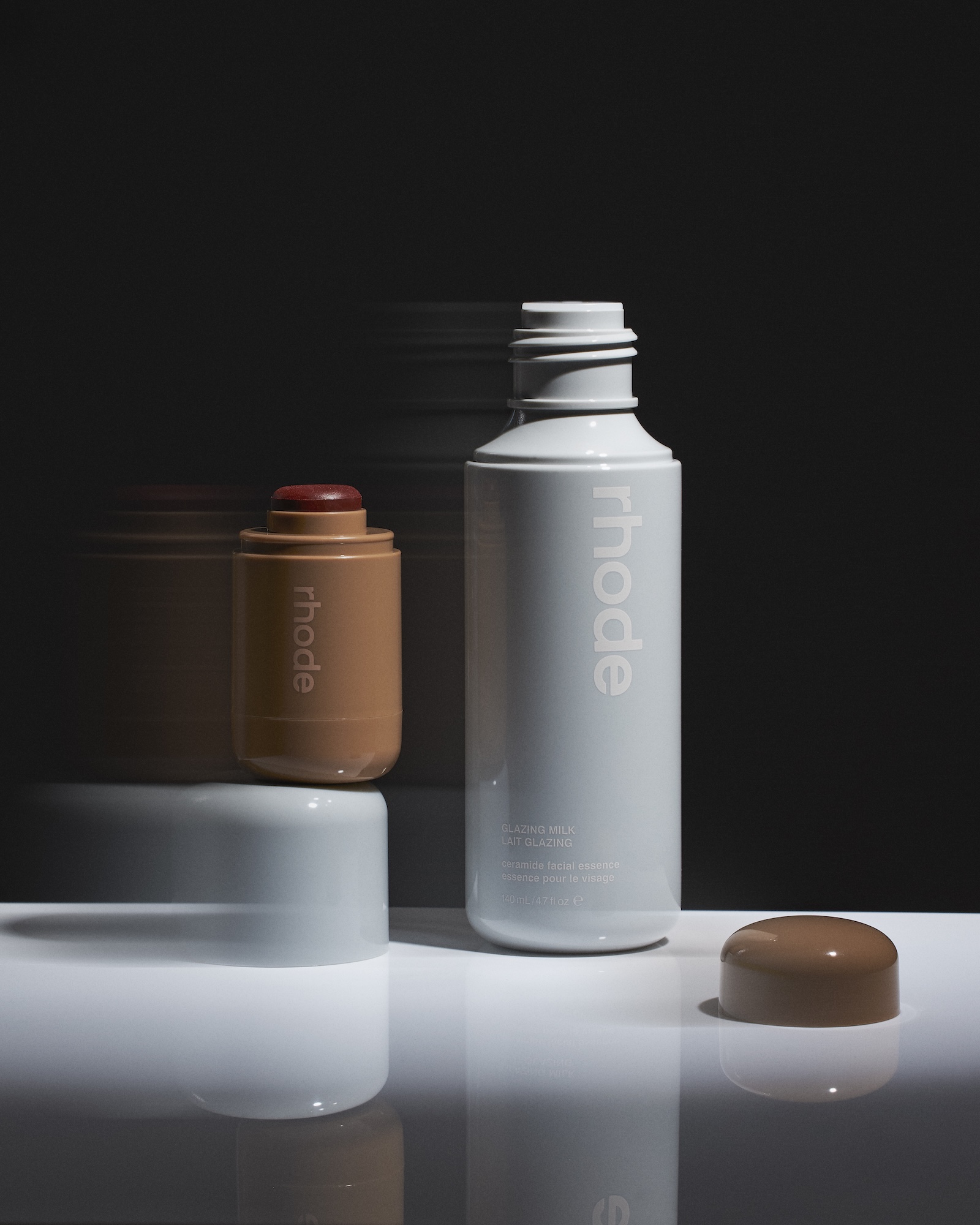 A bottle of Rhode sits on a white table.