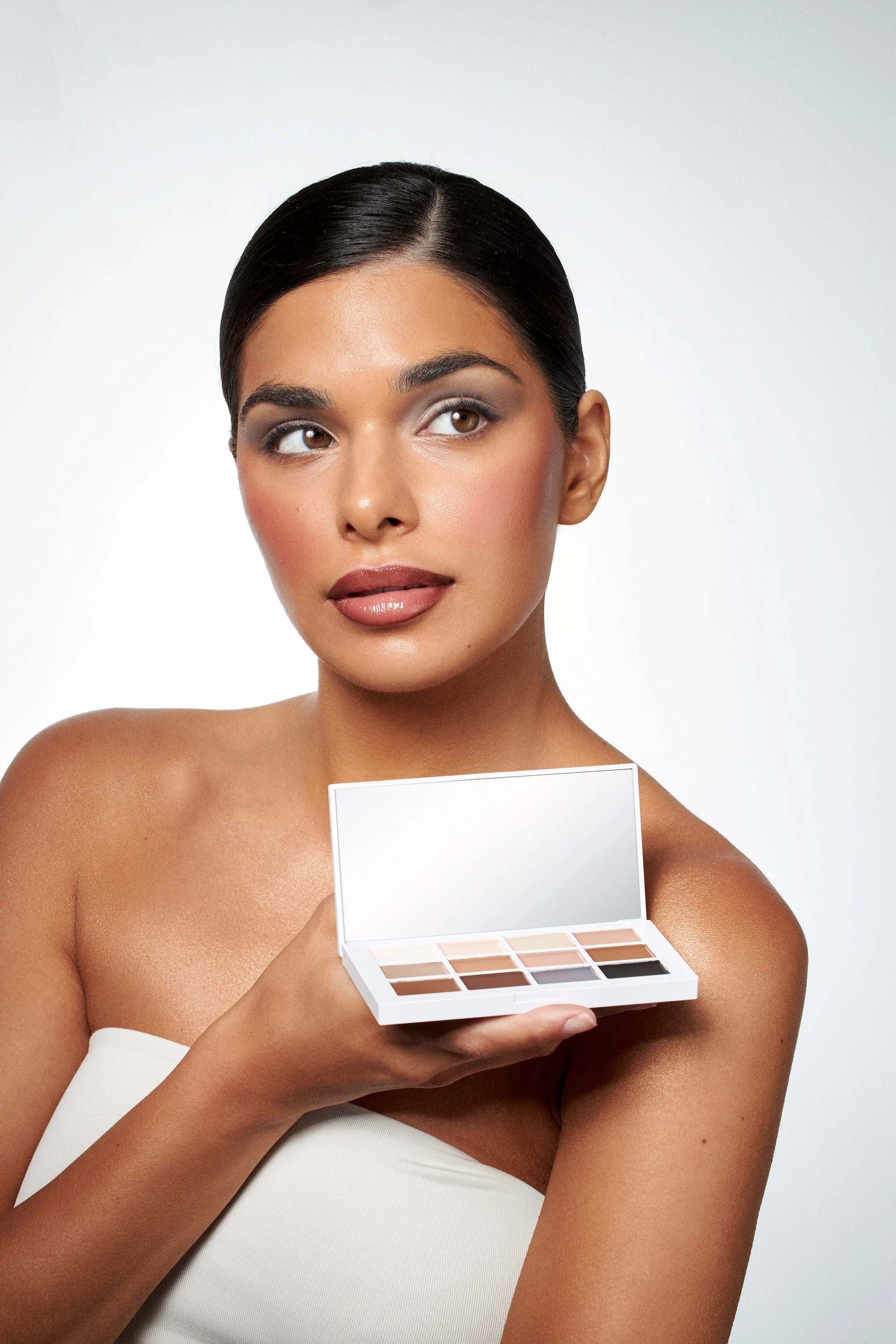 A woman holding a box of makeup by Mario.
