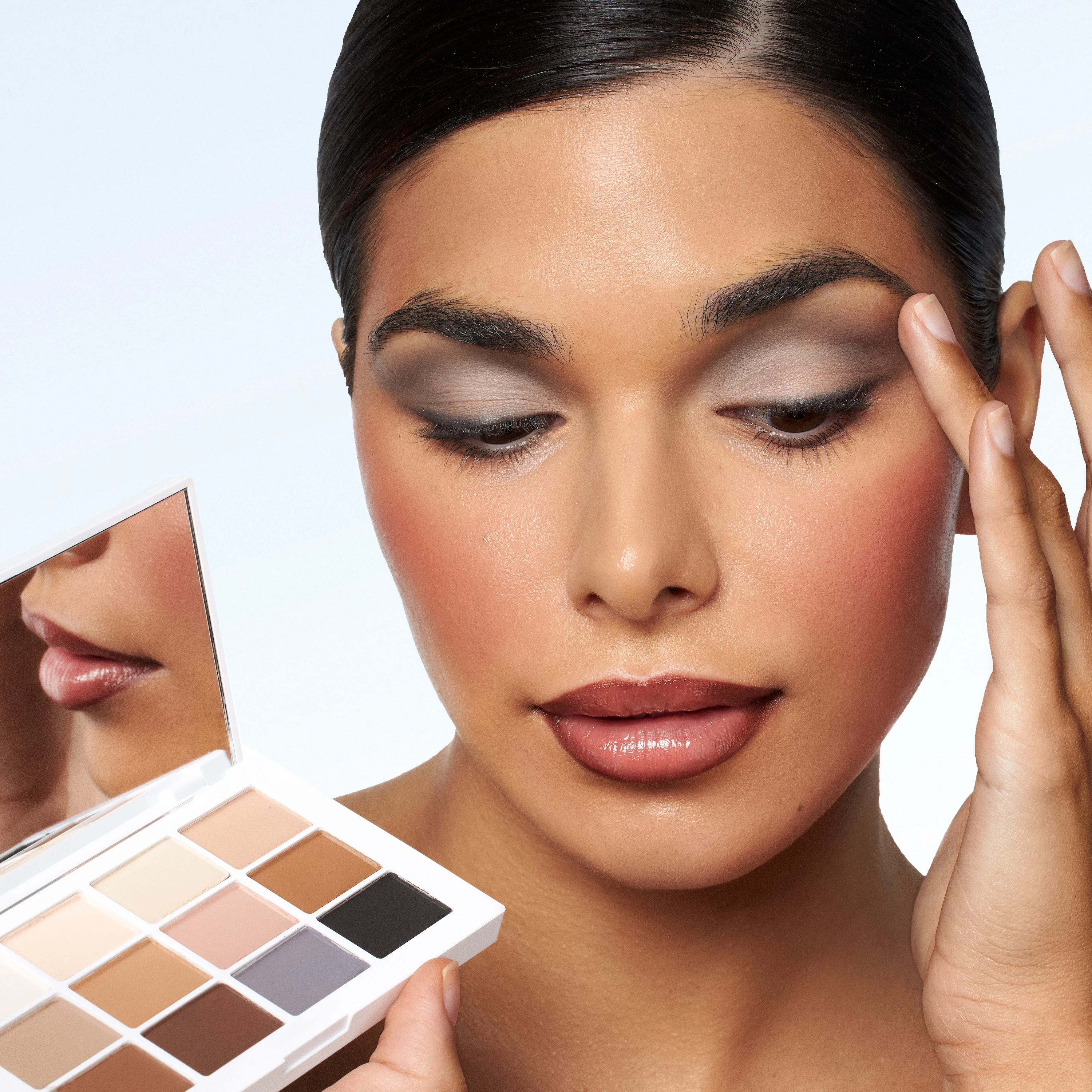 A woman holding a compact mirror with a white powder compact makeup by Mario.