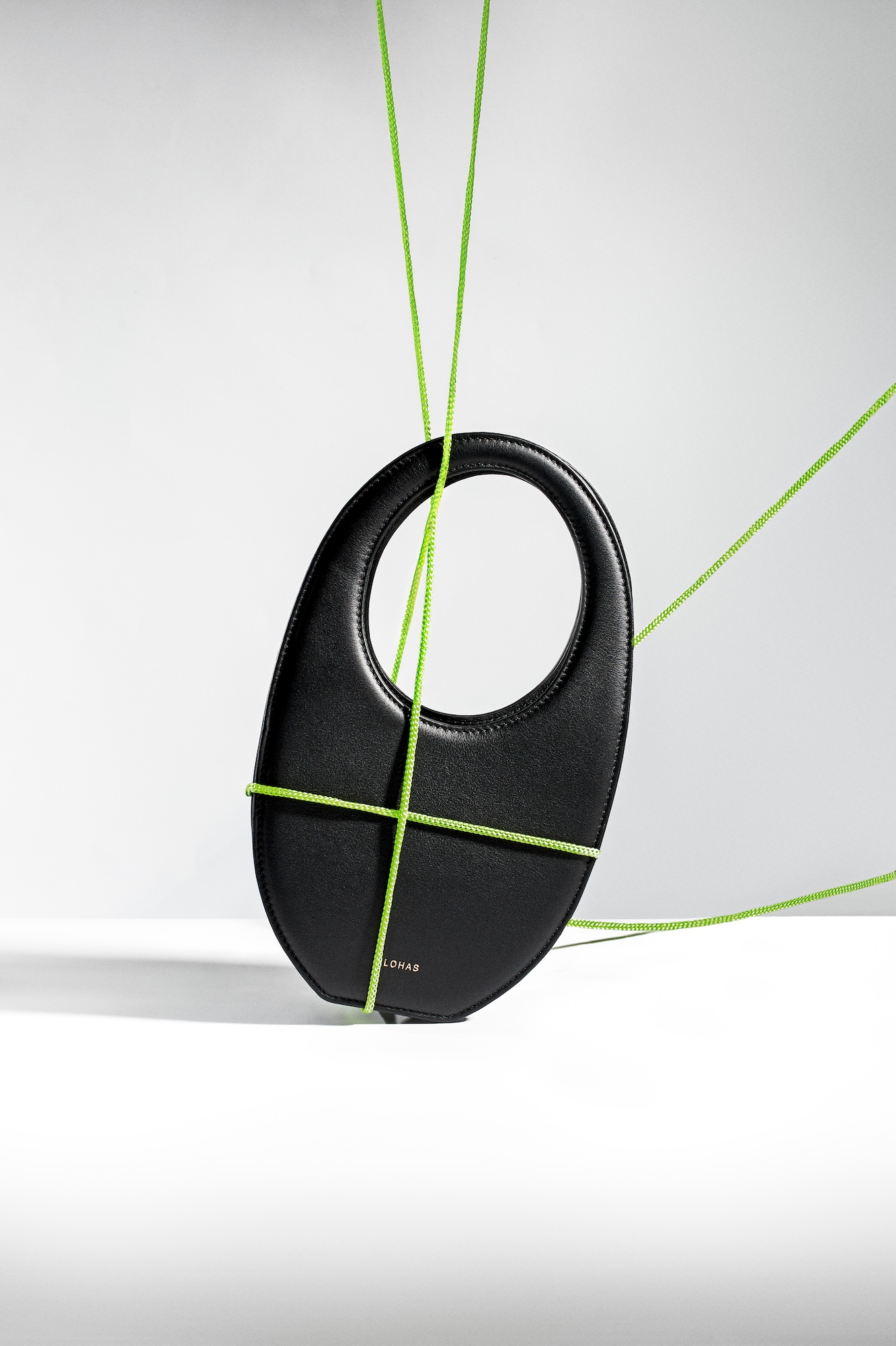 A black purse with a green cord.