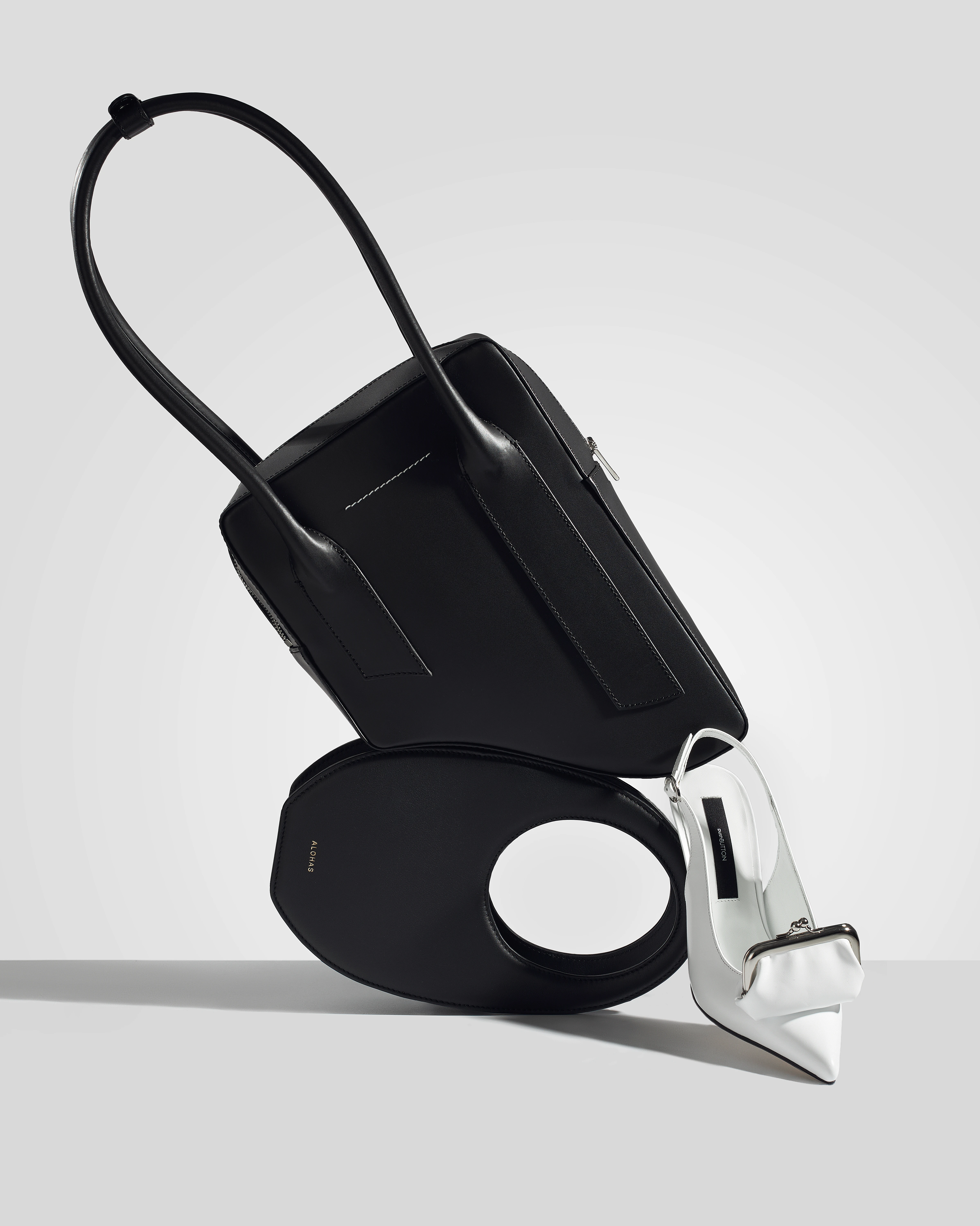 A black purse with a silver handle and a white purse with a silver handle.