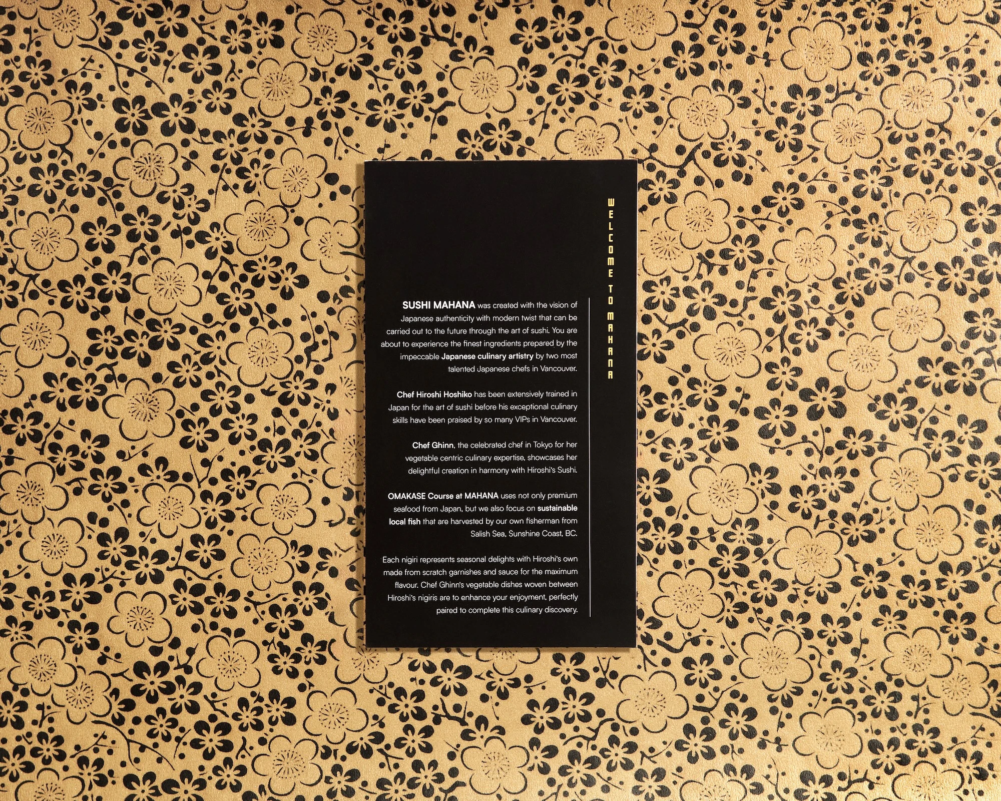 A black and gold booklet menu with a flower pattern on the cover.