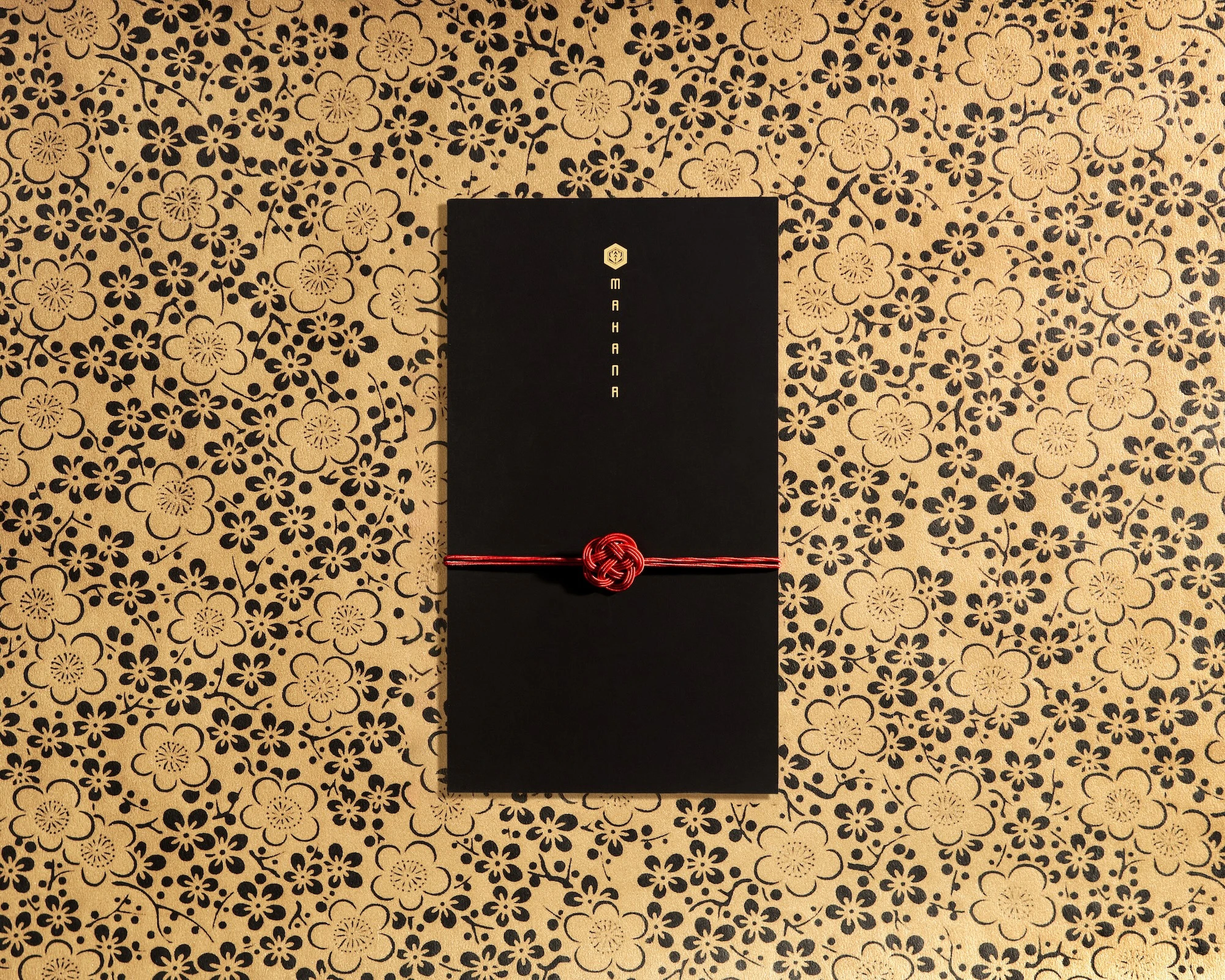 A black and gold booklet menu with a flower pattern on the cover.