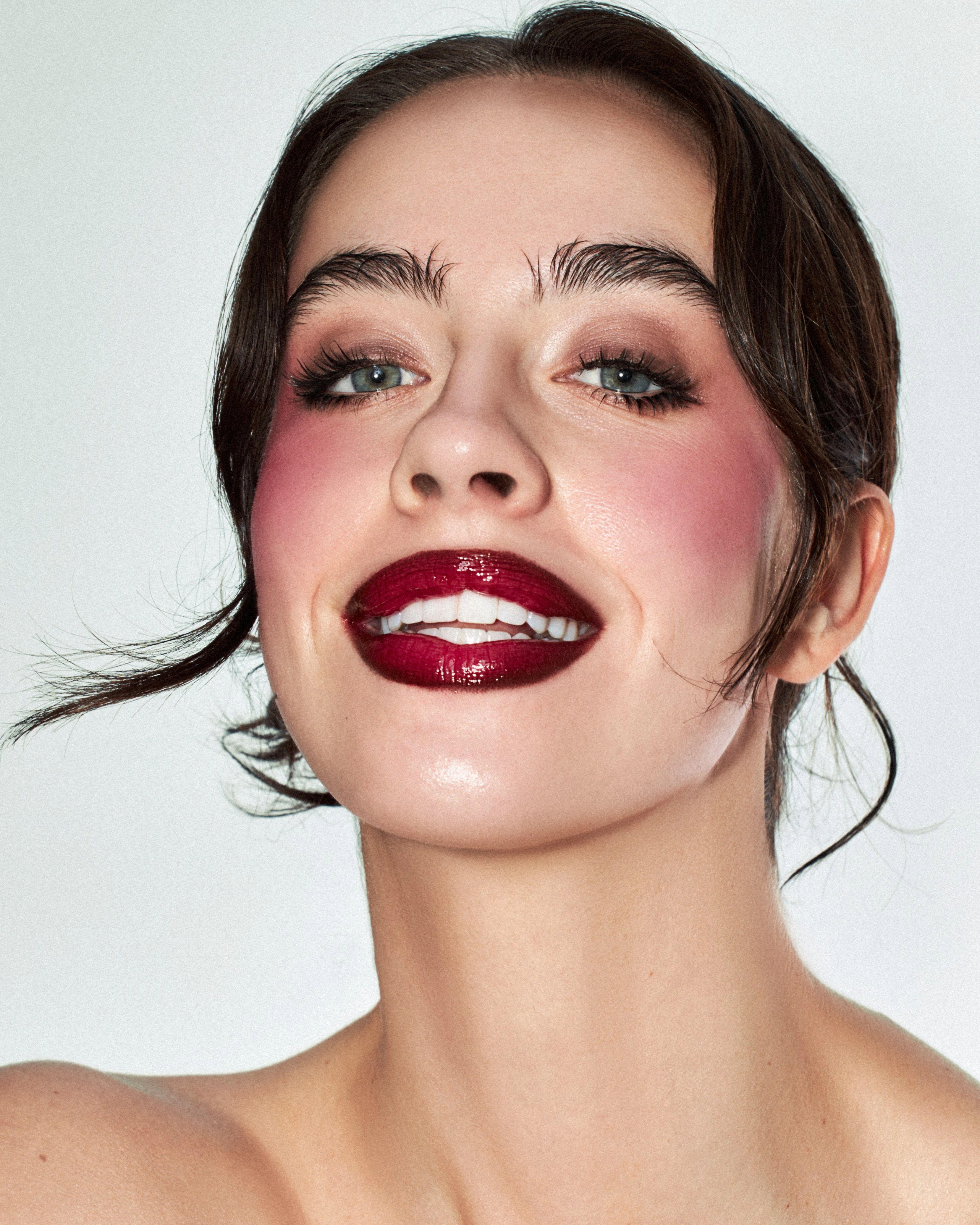 A woman with red lipstick and pink cheeks smiling.
