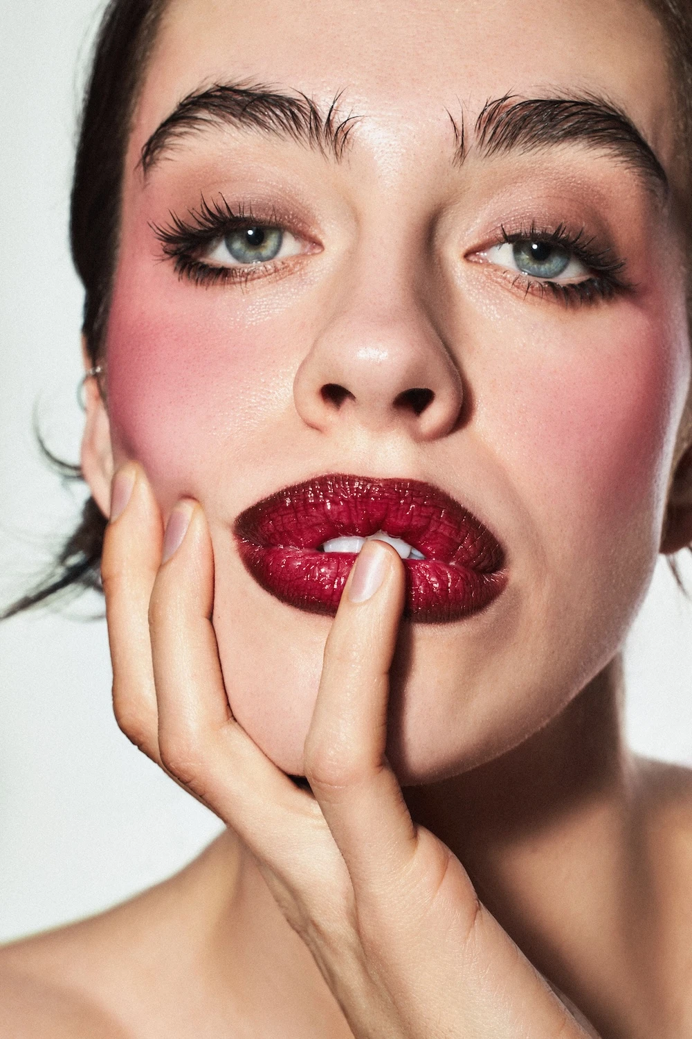 A woman with red lipstick and pink cheeks.