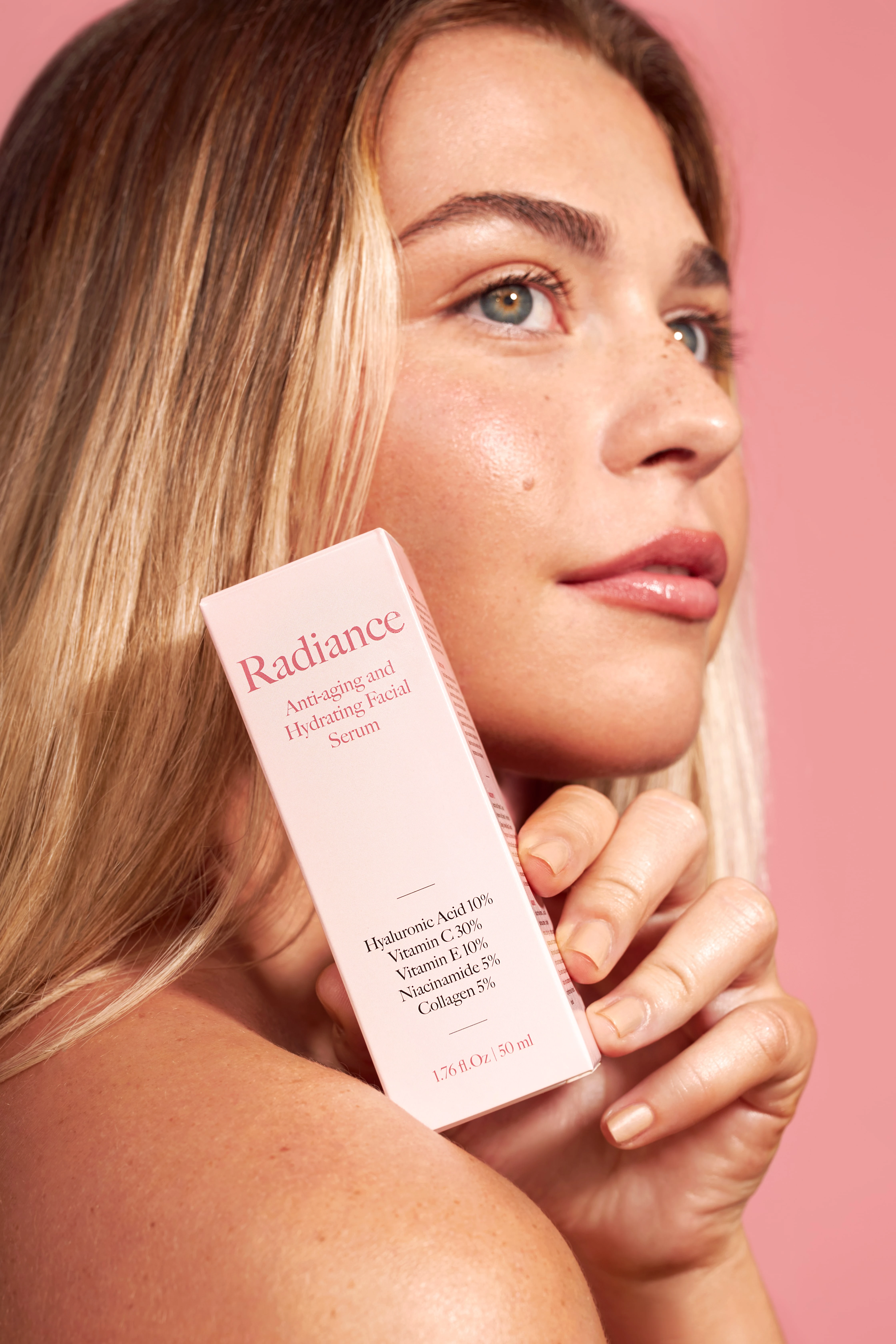 A woman holding a bottle of Radiance anti-aging serum.