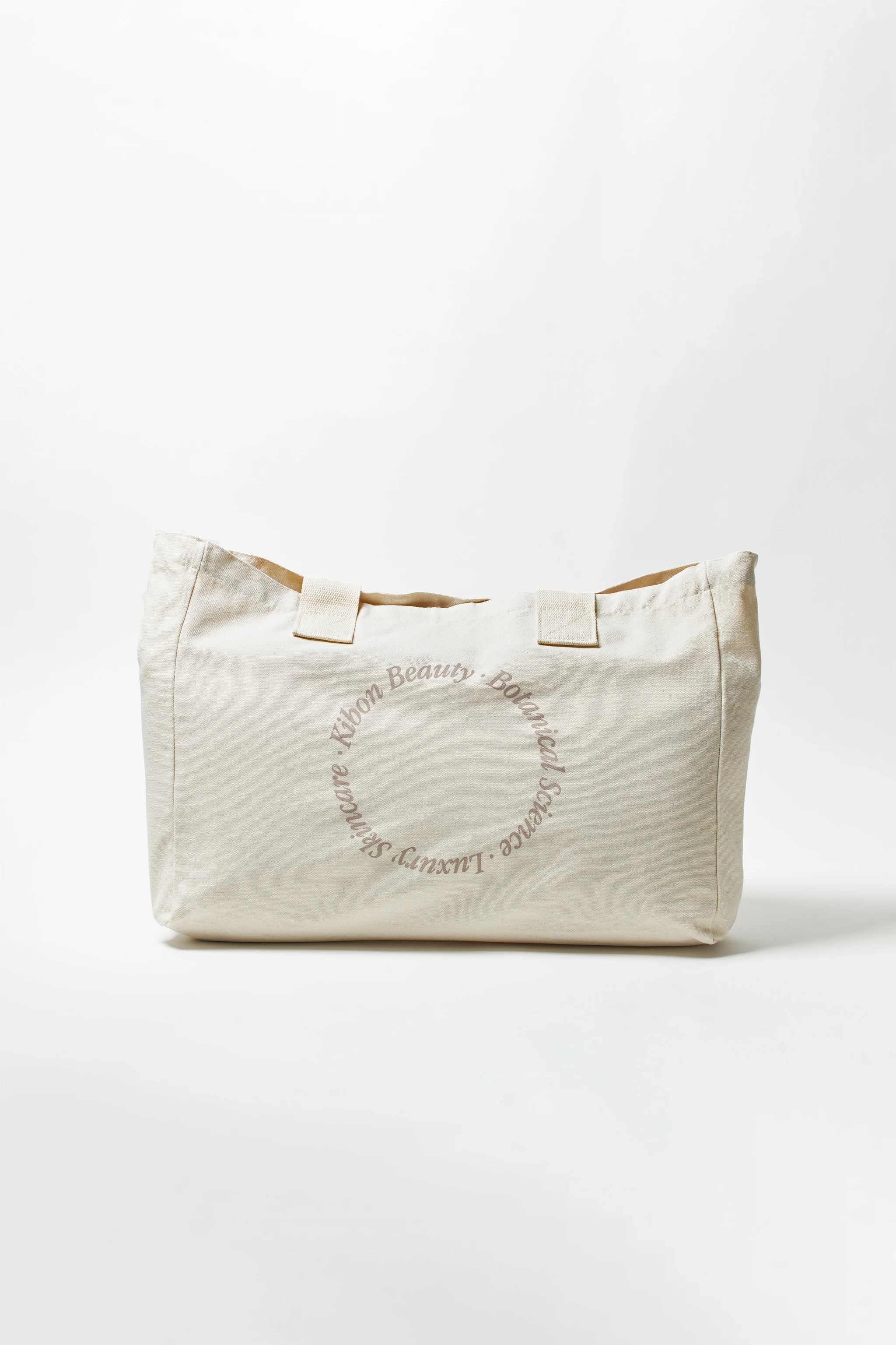 A white canvas bag with a circle on it that says "beauty is in the eye of the beholder".