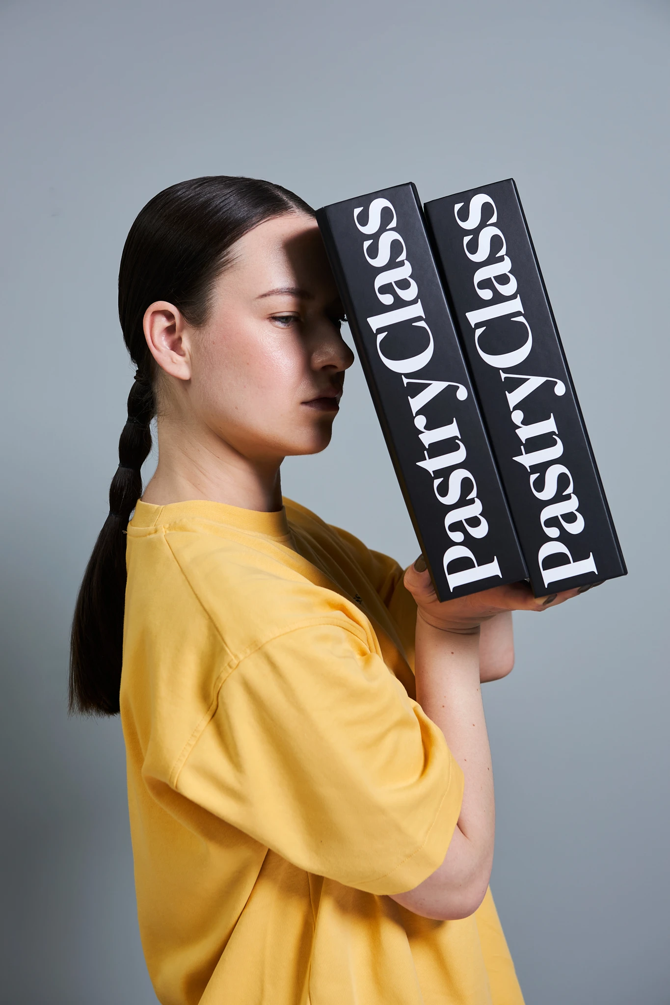A woman with a ponytail holding two books.
