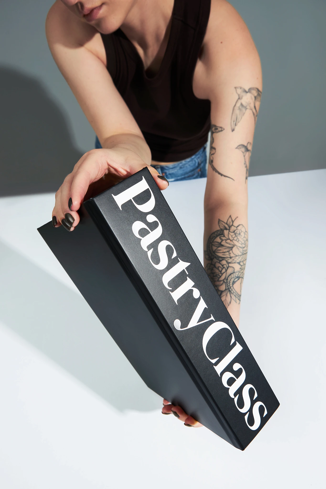 A woman holding a black box that says Pastry Class.