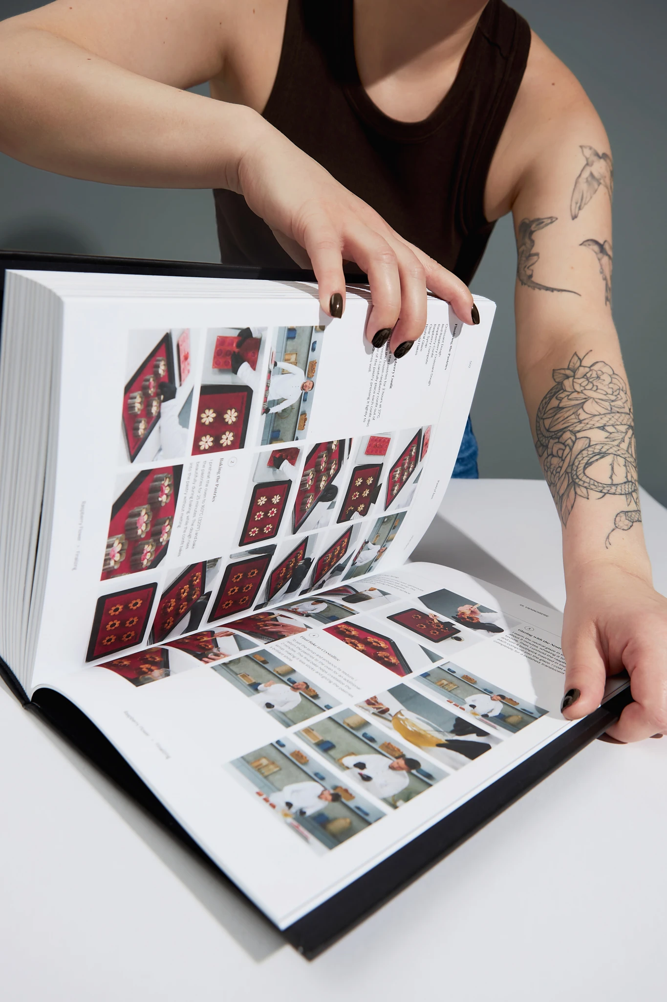 A woman with tattoos is holding a Pastry Class book open to a page with a picture of a bowl of food.