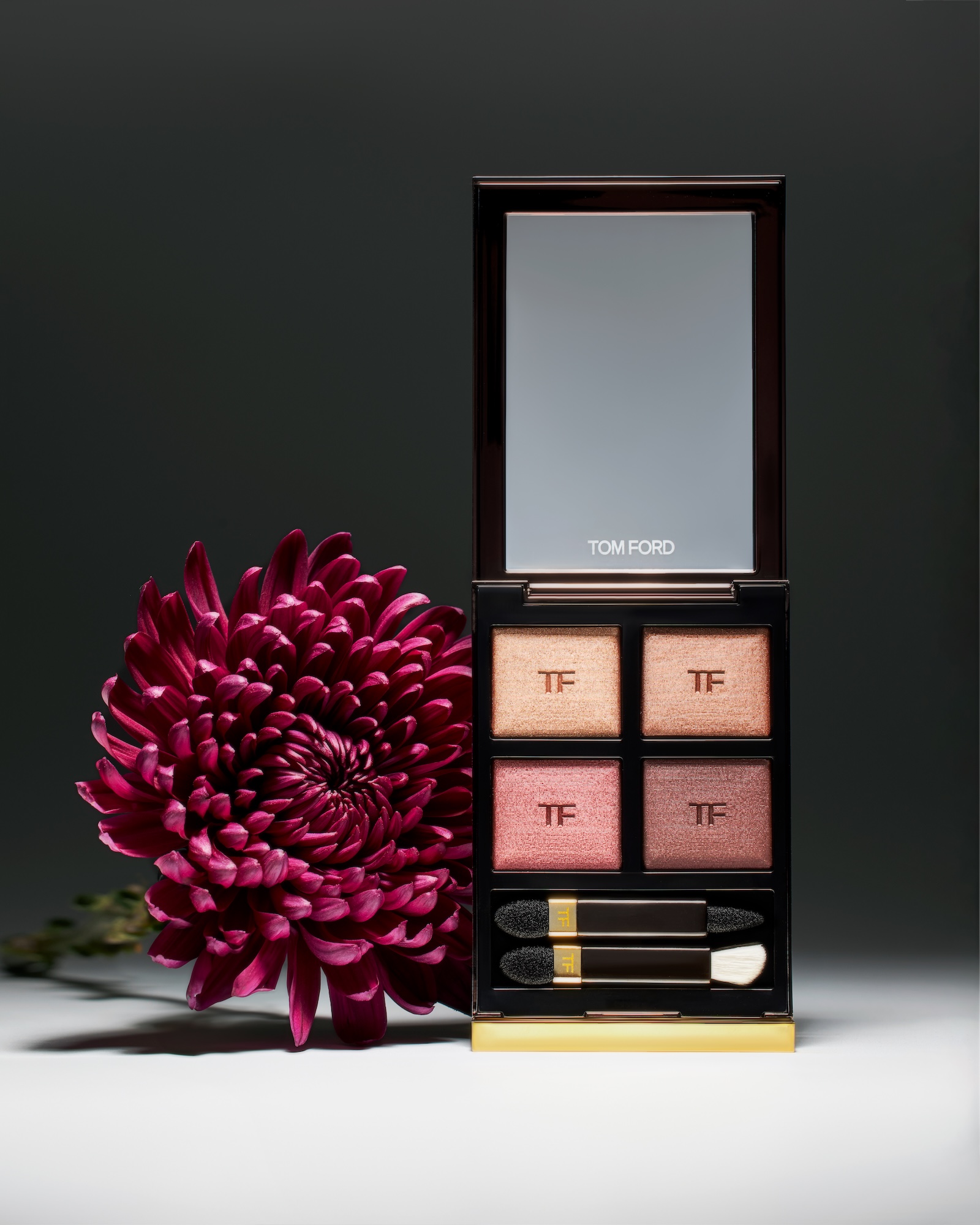 A box of makeup with a pink flower in front of it.