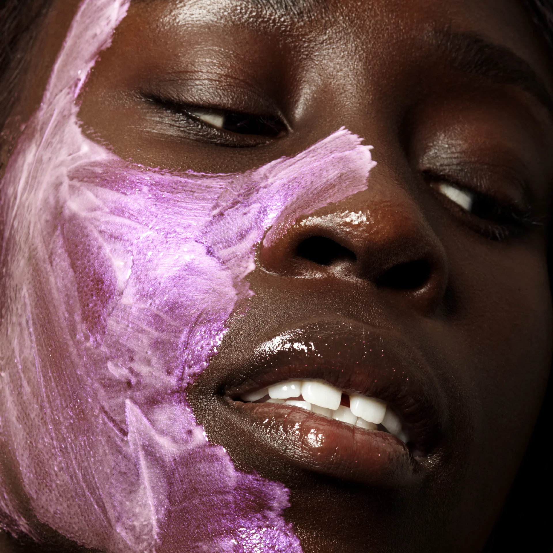 A woman with a purple and white face mask from Comme Deux on her face.