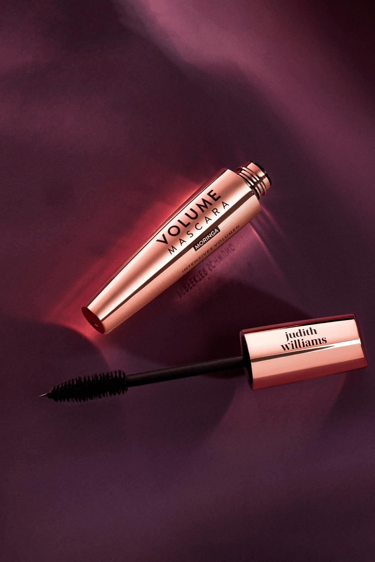 A bottle of Volumebeauty mascara is on a red background.