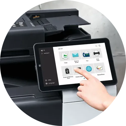 a hand tapping the touch screen of a konica minolta copier