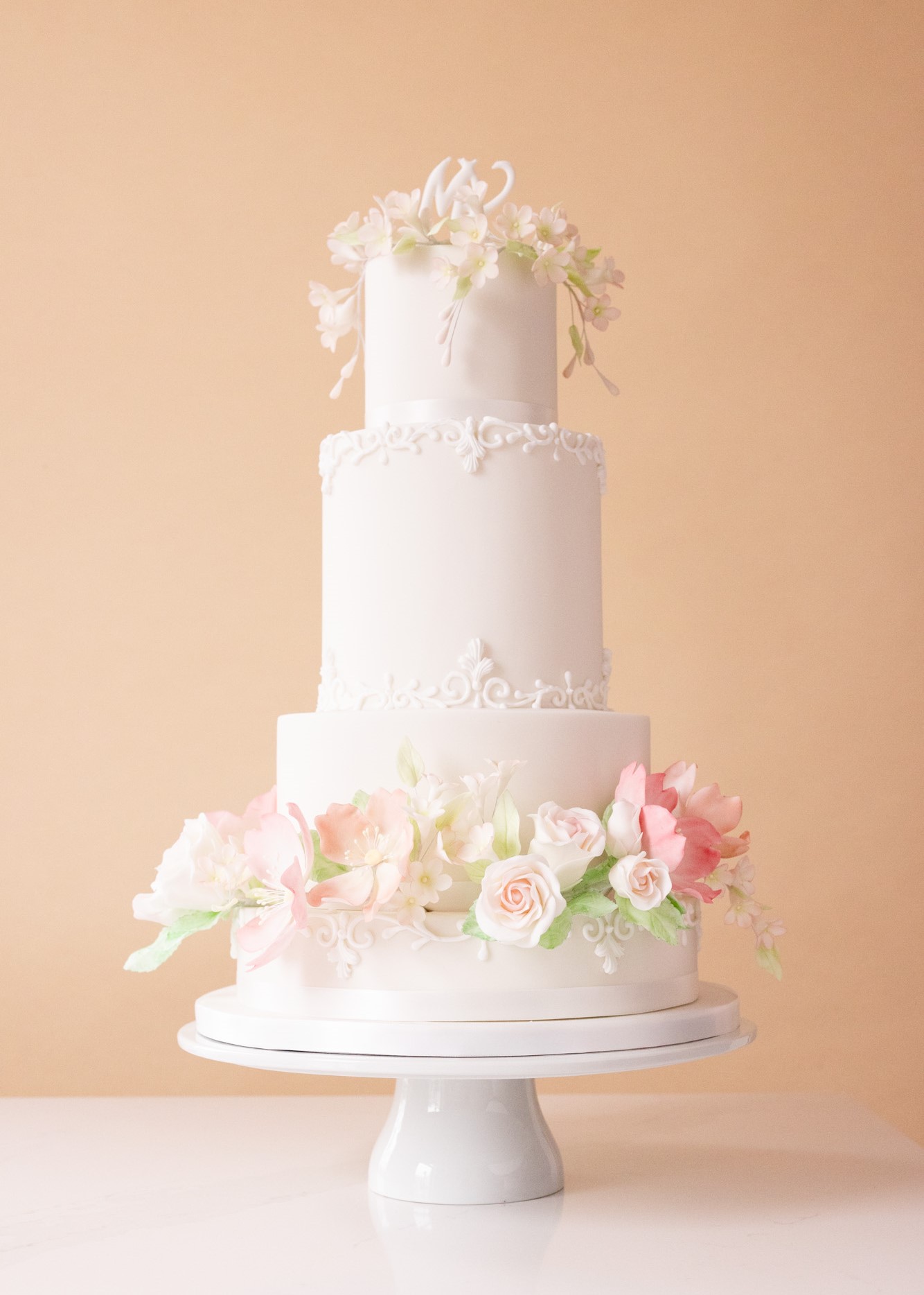 Tiered white wedding cake beautifully decorated with soft coloured hand-crafted sugar flowers