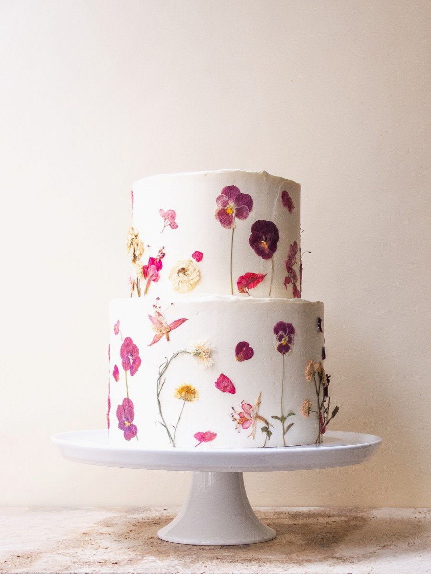 2-tier wedding cake adorned with vibrant pressed edible flowers