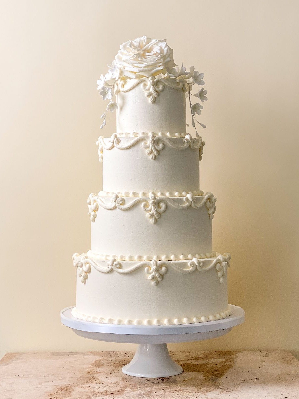 Elegant 3 tier wedding cake with victorian scroll piping and a large white rose sitting on top