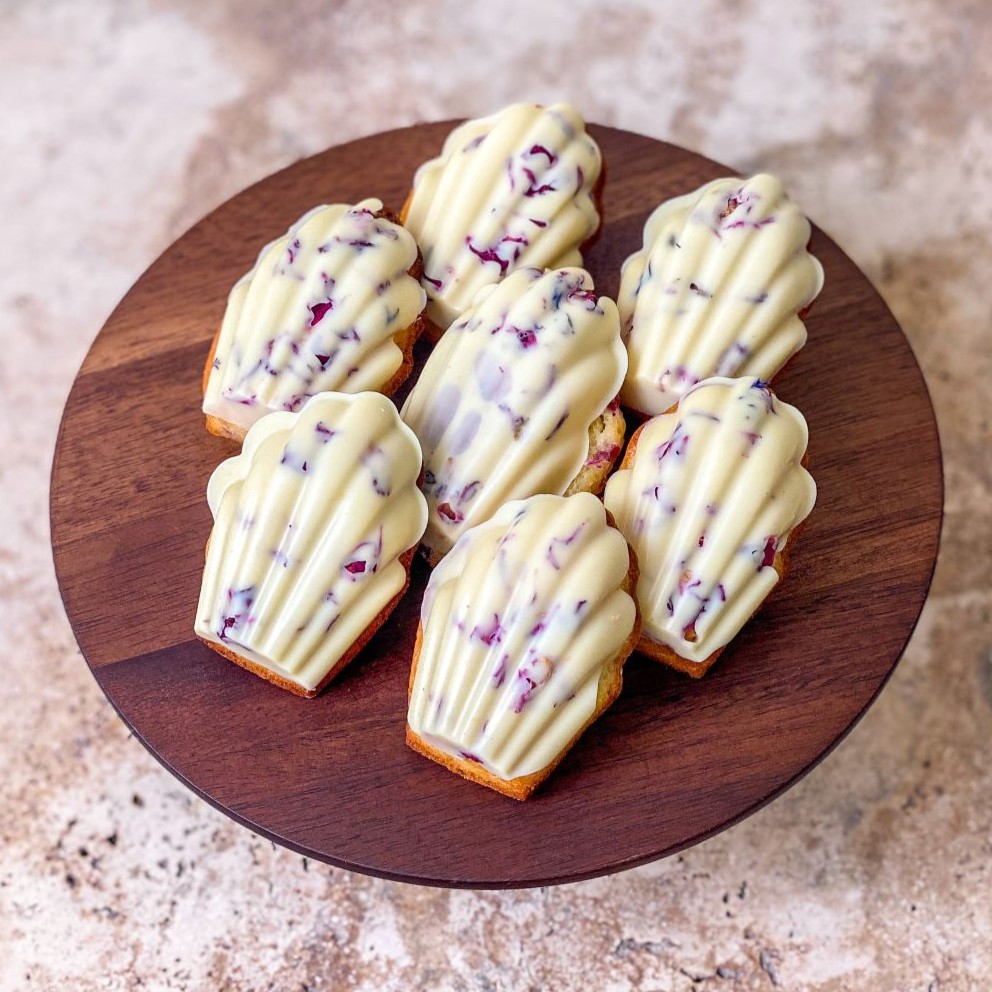 Soft honey madeleines with baked in raspberris and floral white chocolate coat