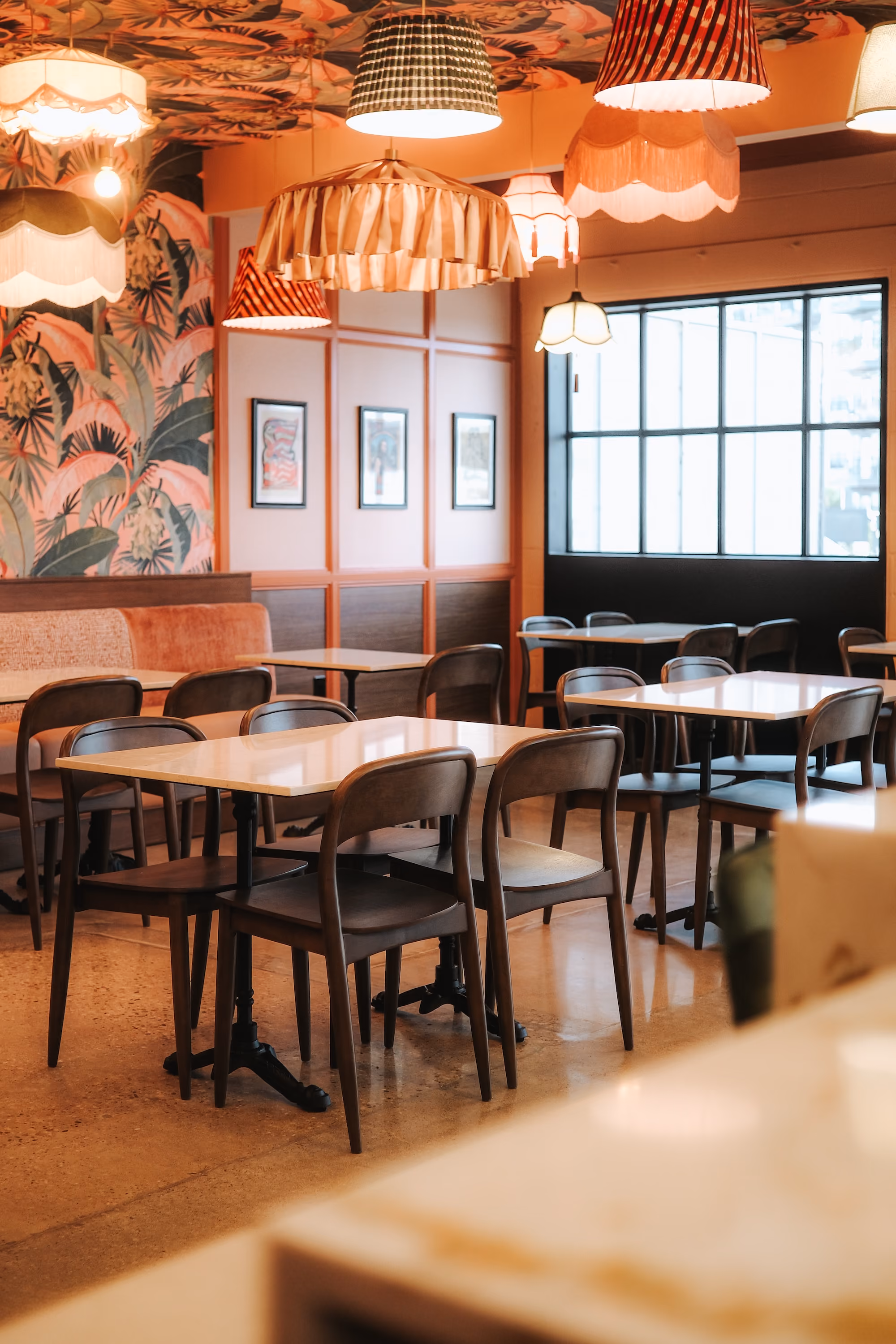 Dining tables set beneath framed posters and tall windows
