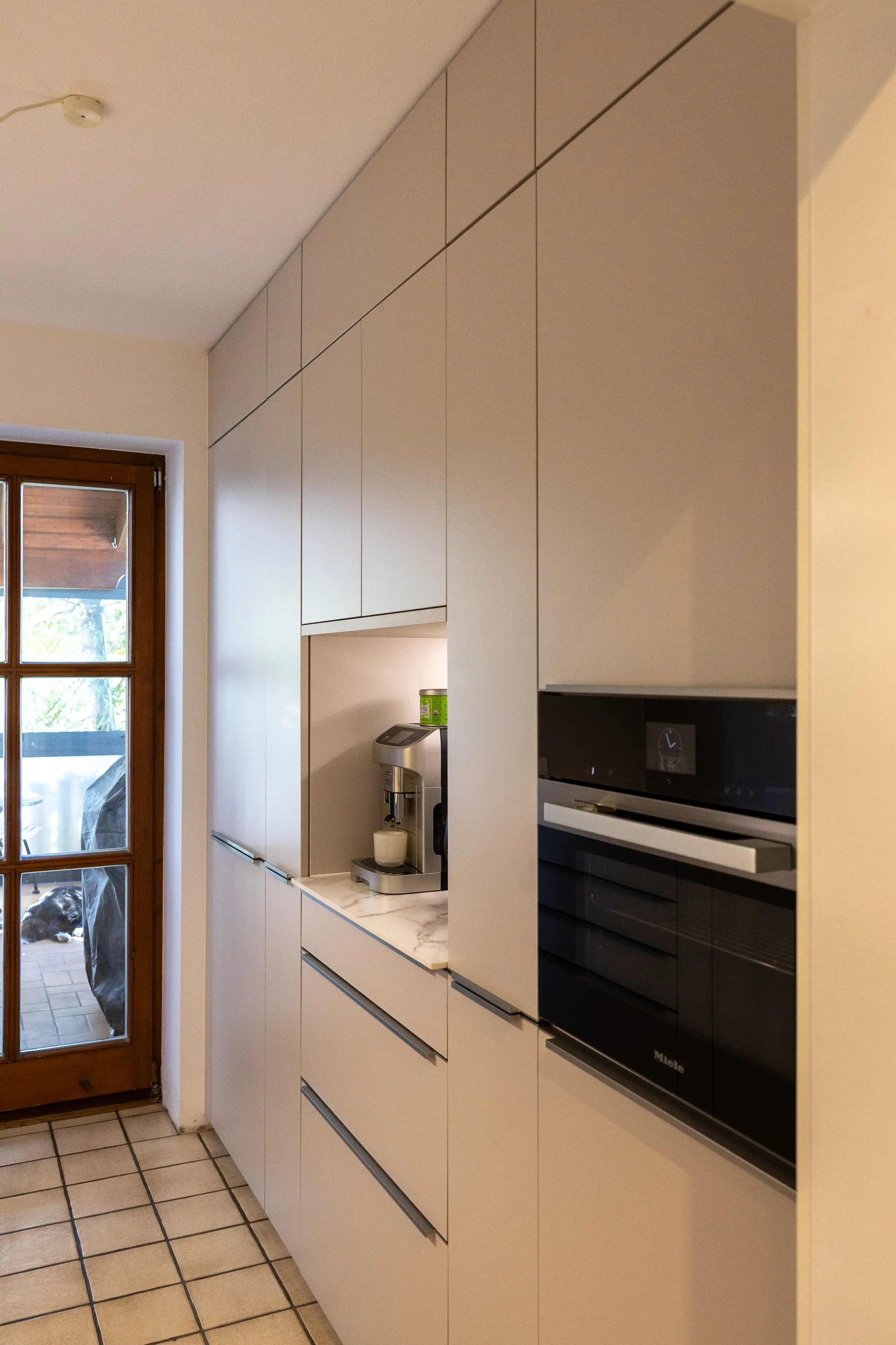 Küche in Sahara mit griffleisten aus Metall Optik und integriertem Miele Dampfbackofen für gesundes Kochen, perfektes Garen und echte Gerätequalität aus dem Thoki Küchenstudio am Wörthsee bei München.