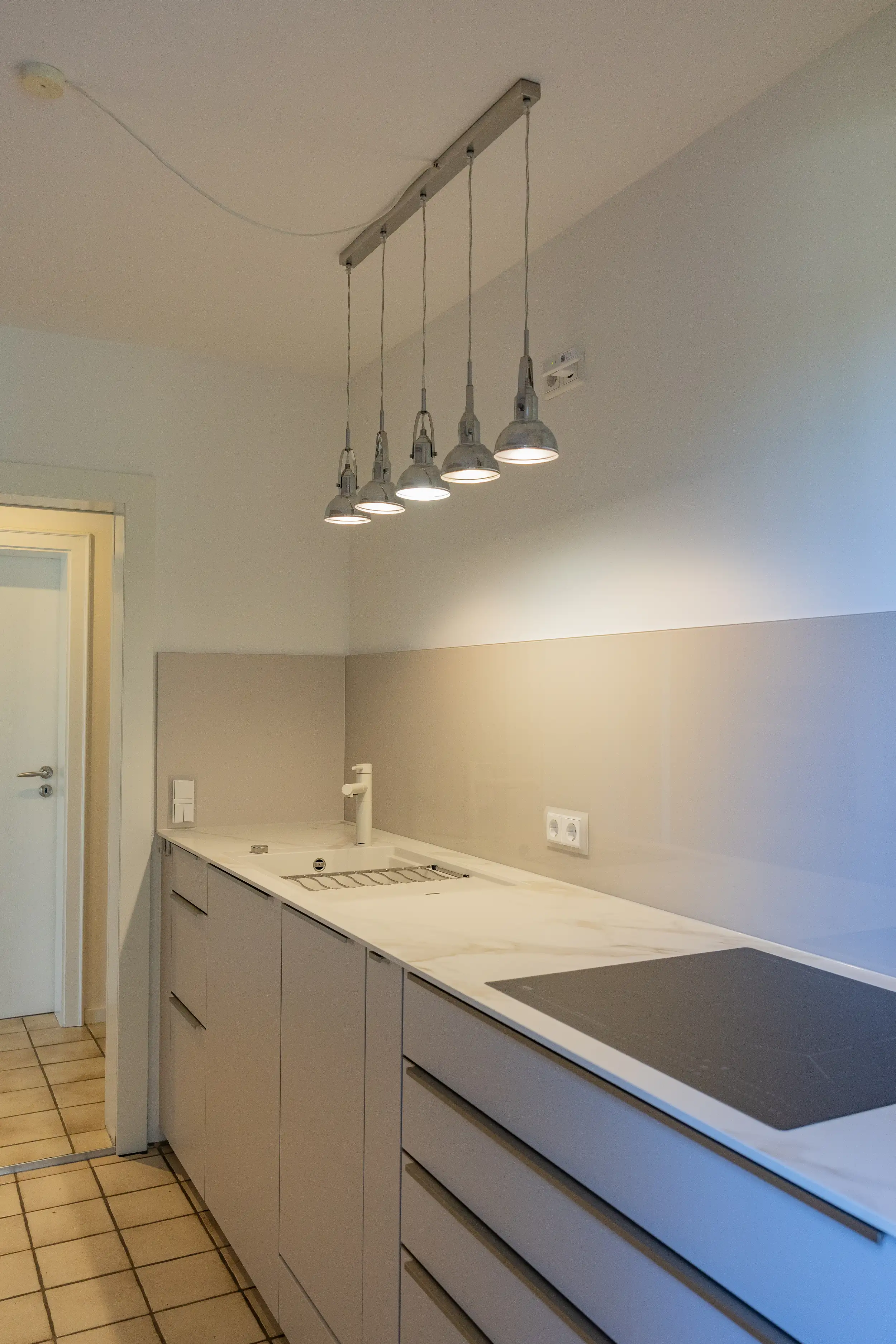 Elegantes AEG Induktionskochfeld kombiniert mit pflegeleichter Glasnische. Diese Grifflose Thoki Küche in Sahara vereint Design und Funktion für moderne Kochbedürfnisse aus Wörthsee bei Starnberg. 
