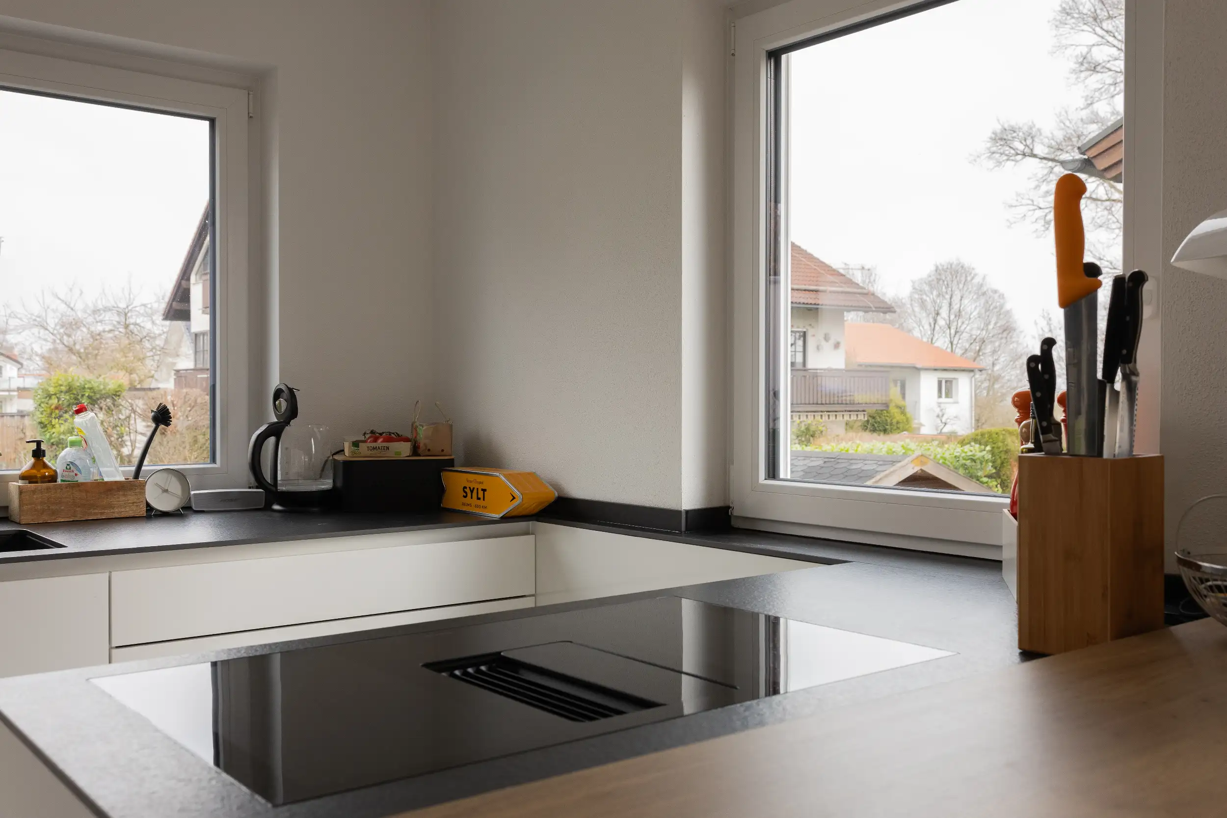 Das Berbel Kochfeld mit integriertem Abzug vereint puristisches Design und patentierte Technik. Die grifflose Kochinsel mit Blick nach draußen wird zum Herzstück der Küche.